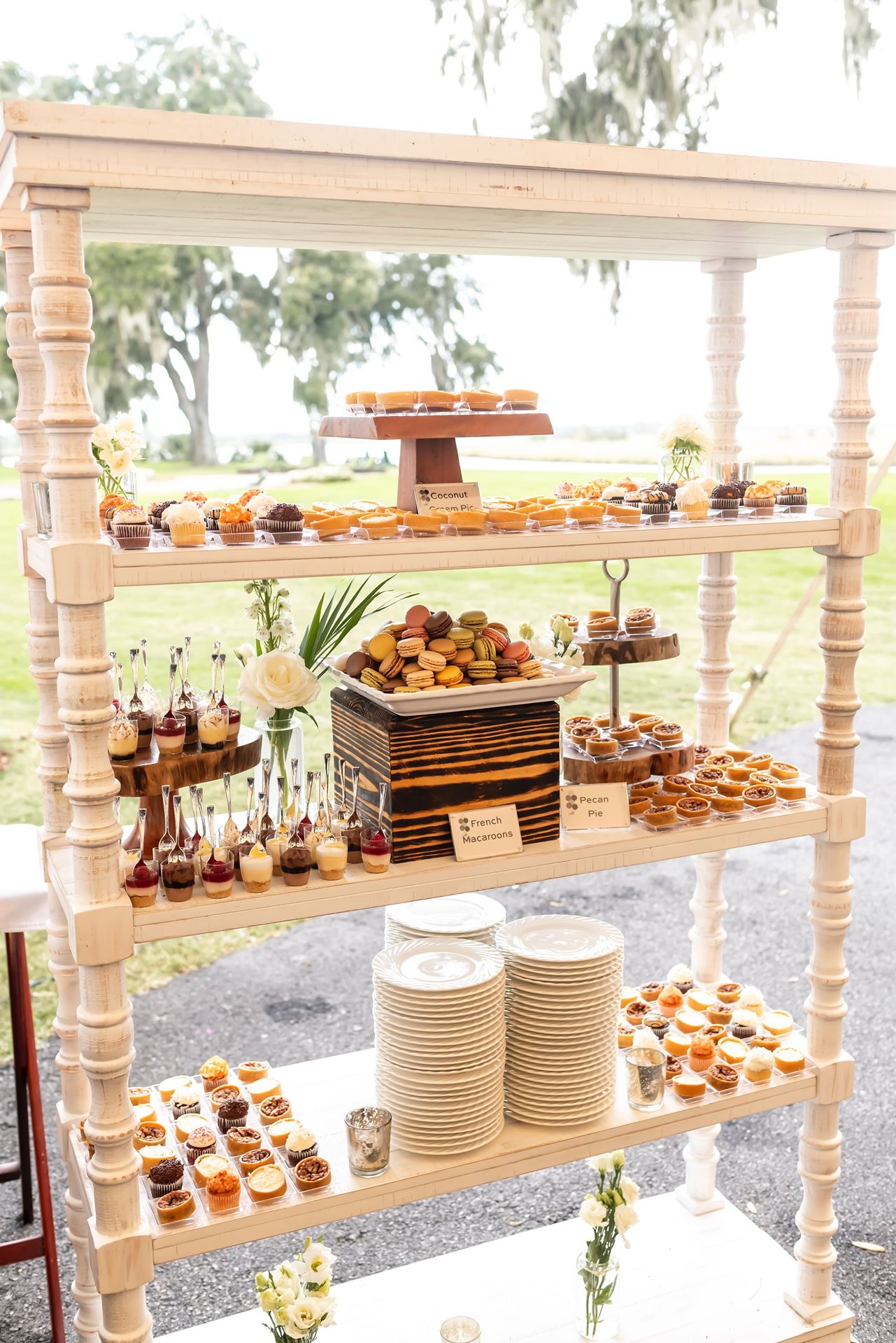 Elegant dessert display shelf with cupcakes and plates arranged on wooden tiered stands.