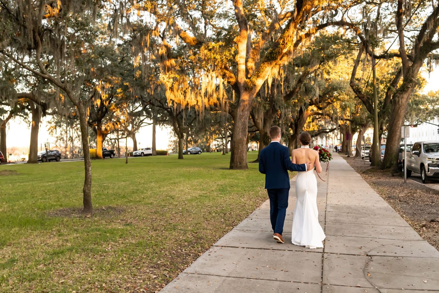 Spanish moss hangs from oak trees over a garden pathway during a golden sunset in the southeastern United States.