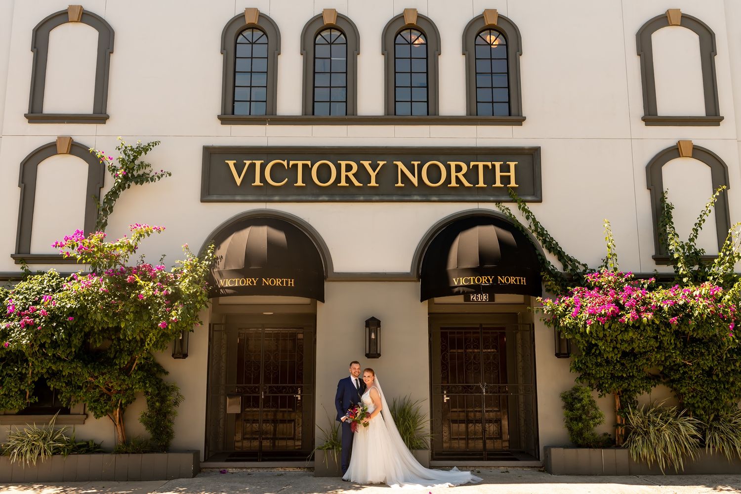 Exterior views of Victory North historic wedding venue with arched windows and pink flowering plants in Savannah.