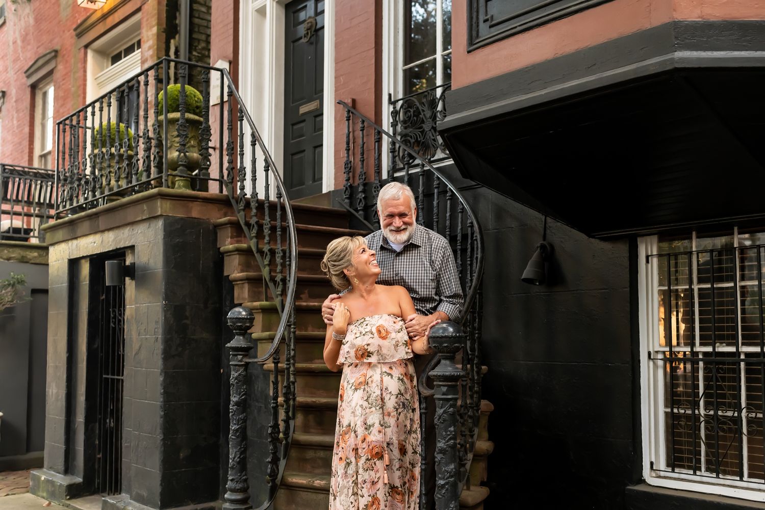 A brownstone rowhouse with steps leading to the entrance on a sunny urban street.