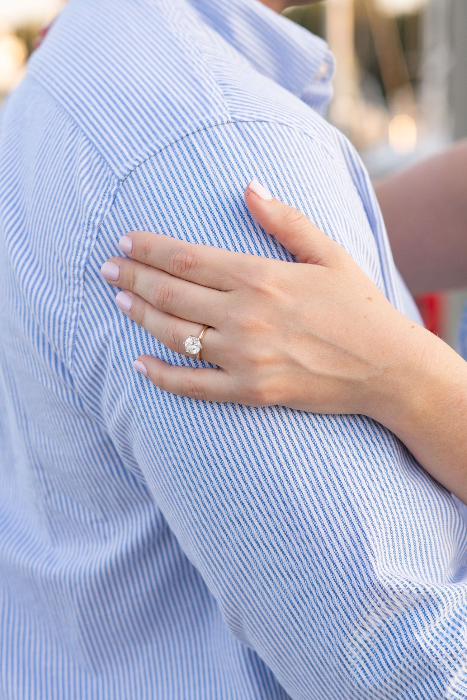 Close-up view of hands gently resting on a light blue and white striped dress shirt fabric.