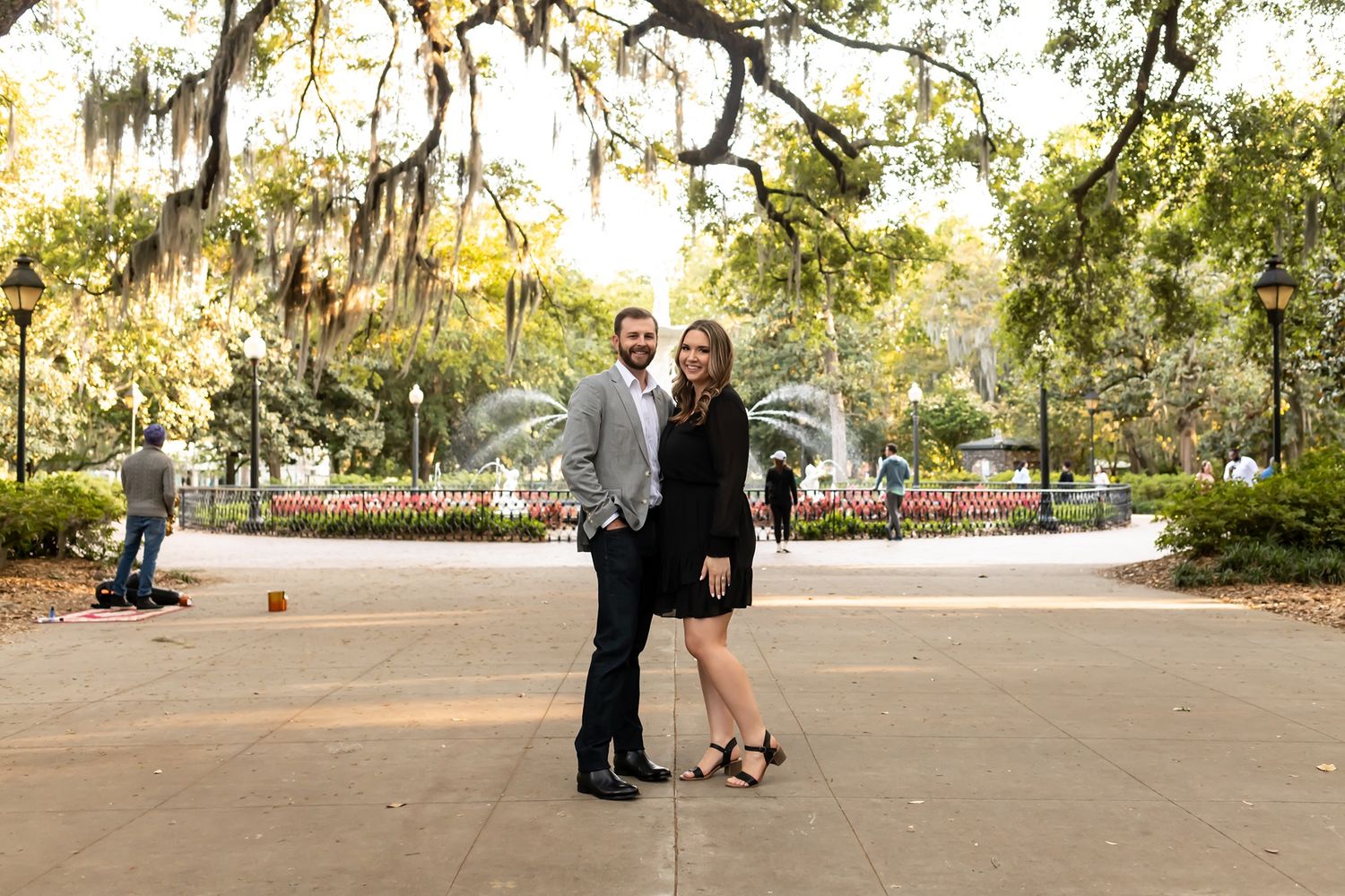 Urban wedding photo session in a park with greenery and sunlight filtering through the trees during a beautiful autumn day.