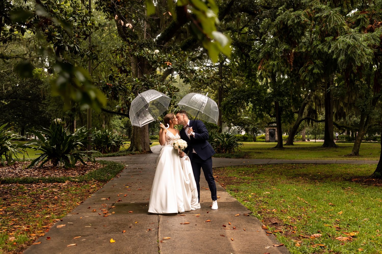 A couple celebrates their wedding day surrounded by lush greenery in a tranquil park setting.