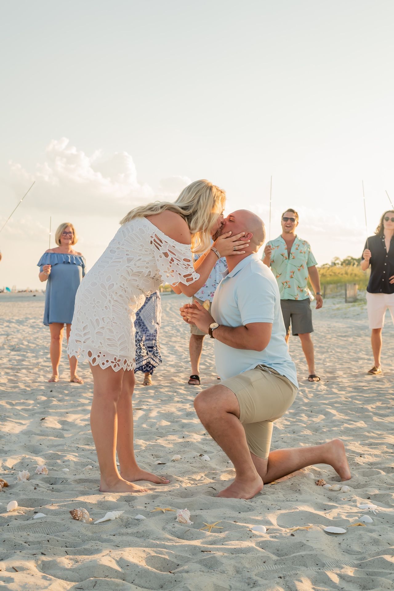 A sequence of beach proposal photos showing someone getting down on one knee on sandy shores at sunset.