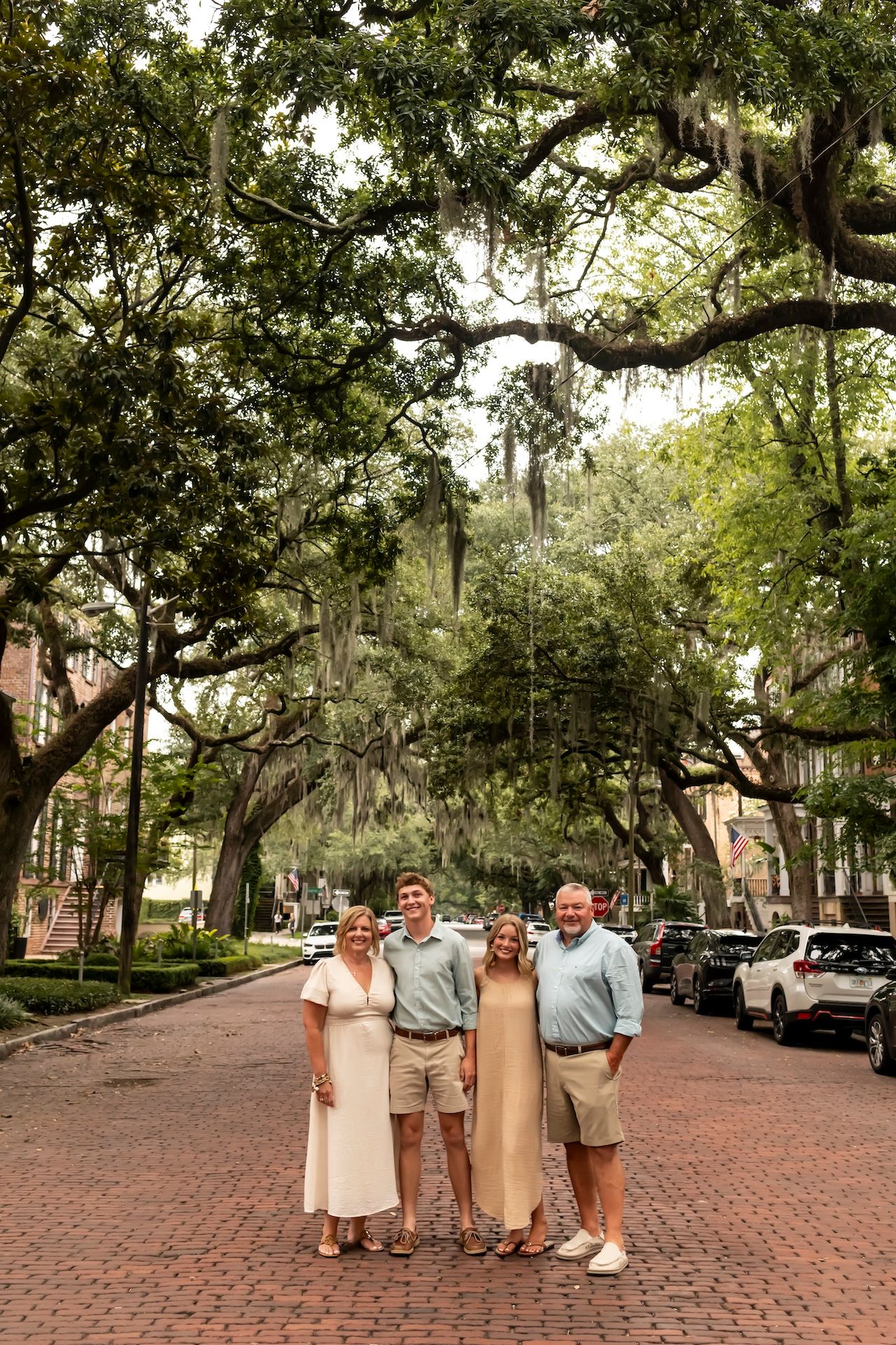 Spanish moss drapes over a picturesque brick-paved street lined with oak trees in historic Savannah, Georgia.