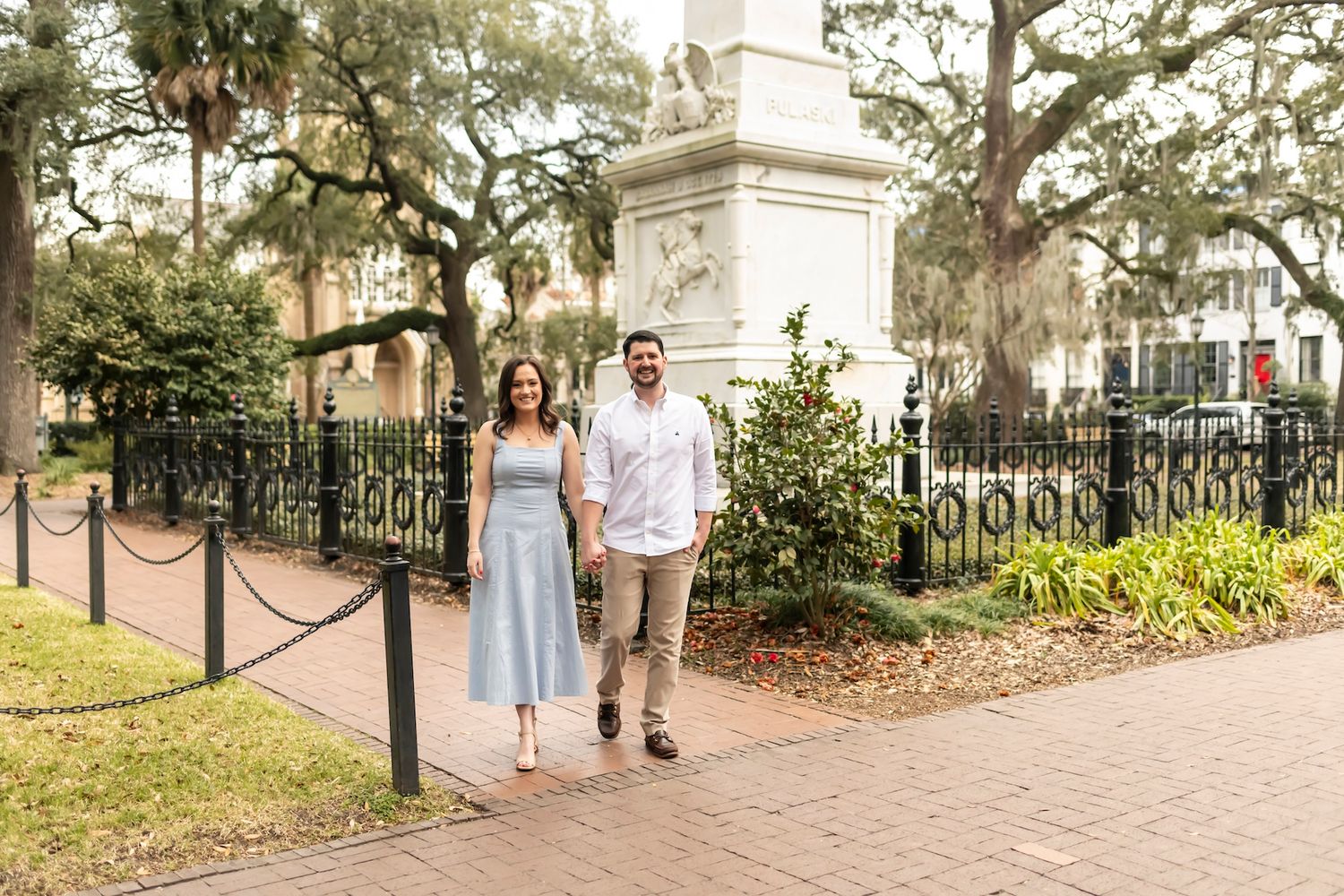 A couple takes a romantic stroll along a brick pathway shaded by Spanish moss-draped oak trees.