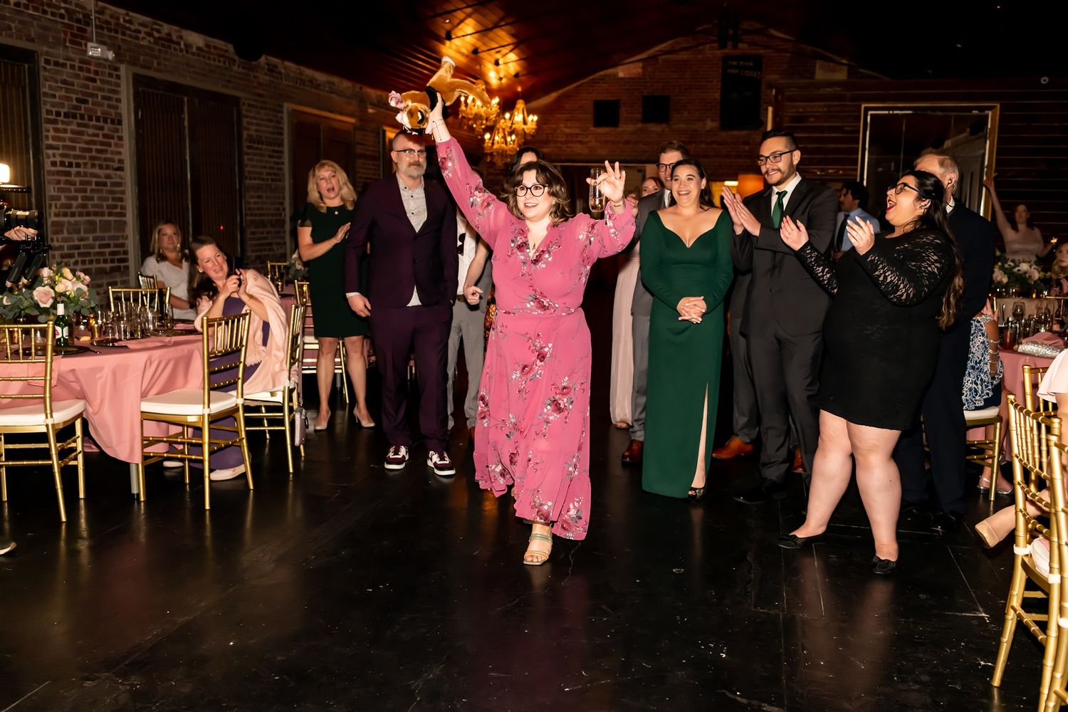 Dance party on wooden dance floor with chandelier lighting at indoor venue during celebration.