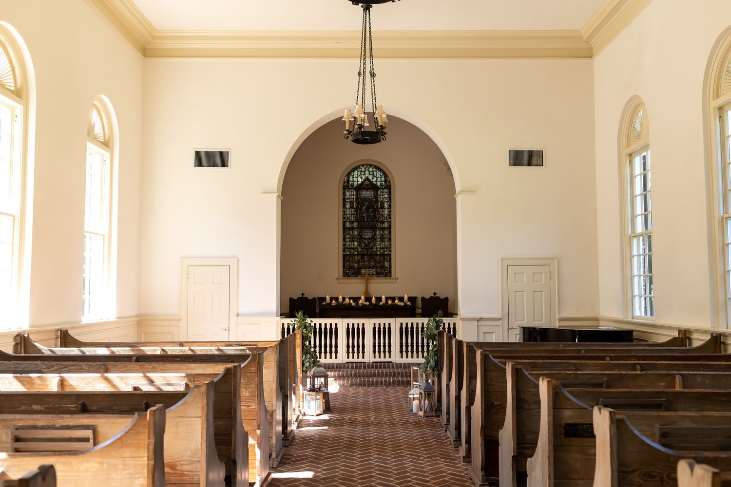 A panoramic view inside a traditional church sanctuary with white walls, wooden pews and natural light streaming through windows.