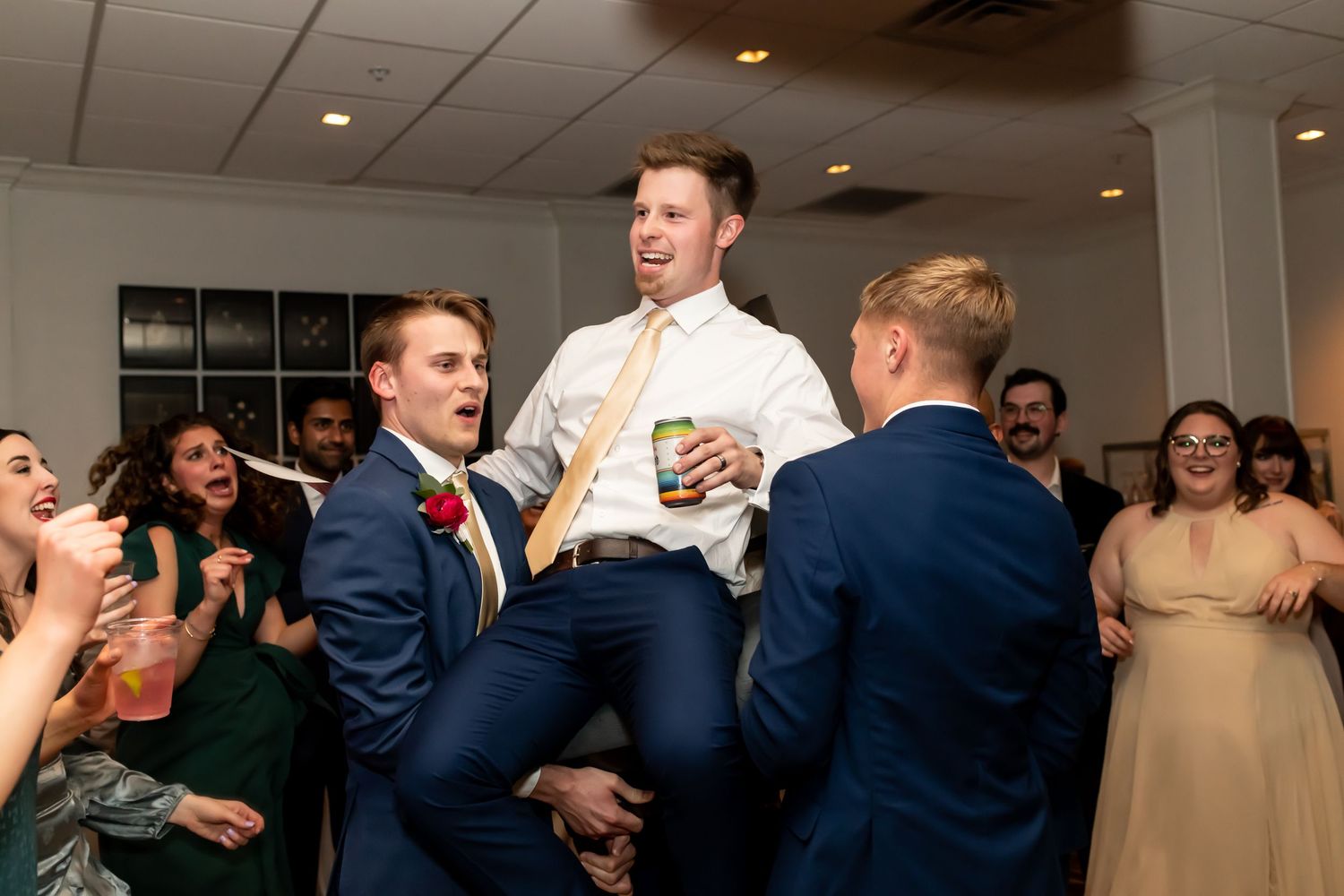 Guests on a dance floor at a wedding reception celebrate and dance together in formal attire.