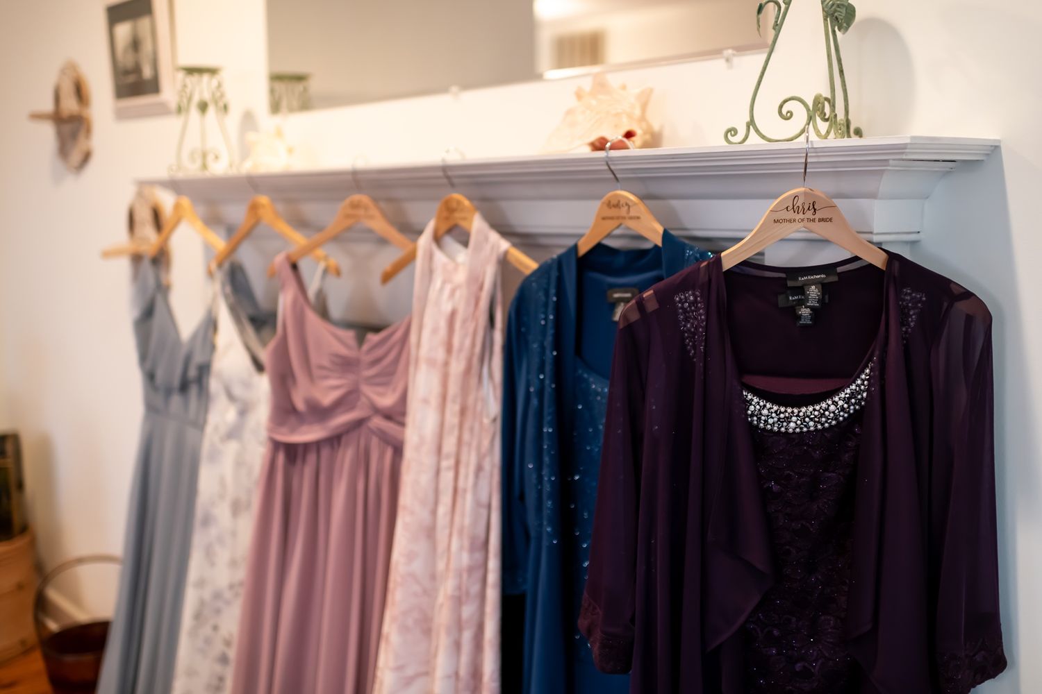 A retail clothing store interior with wooden hangers displaying purple and navy blue garments on white racks.