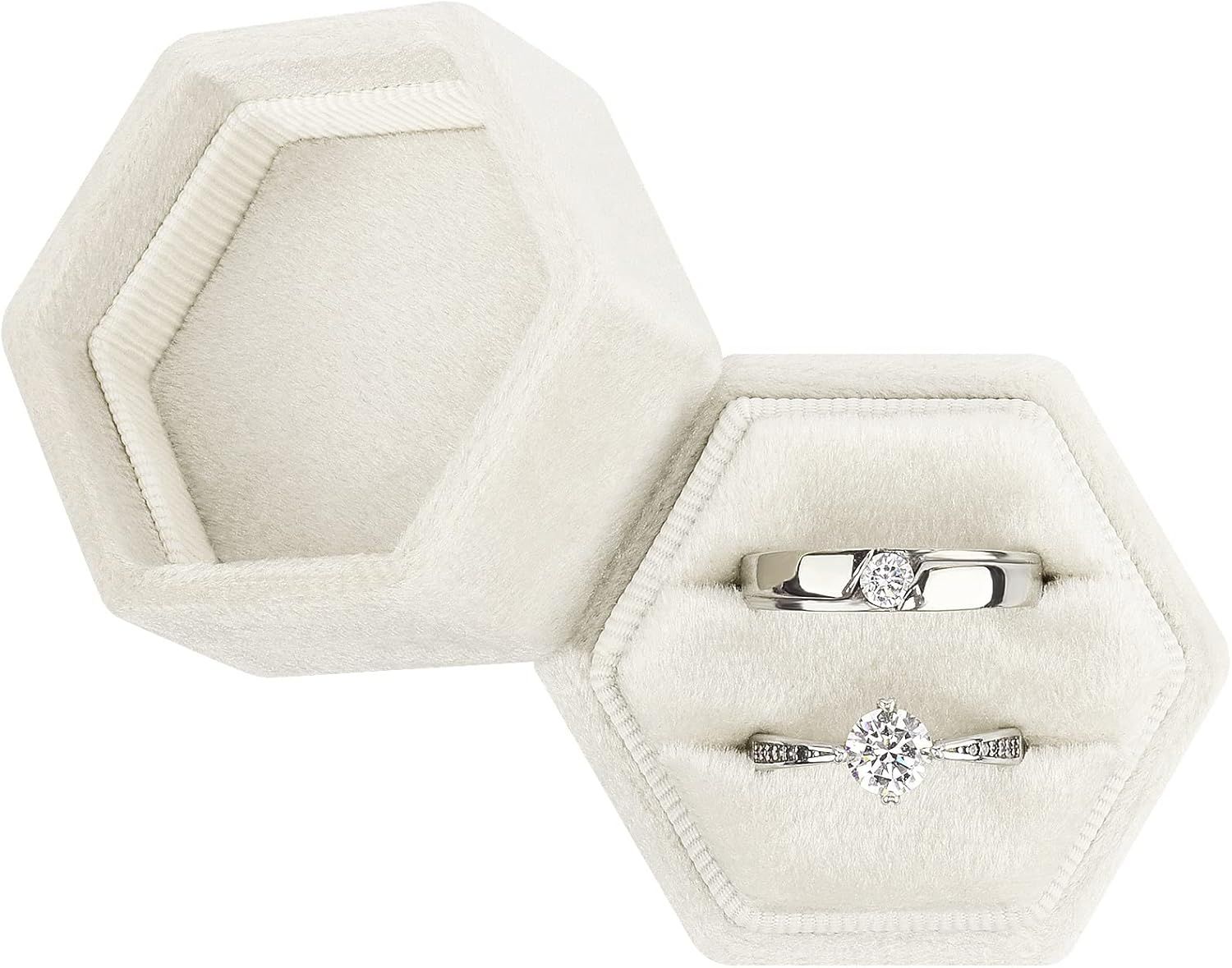 White hexagonal velvet ring box holds two elegant engagement rings against plush interior cushioning.
