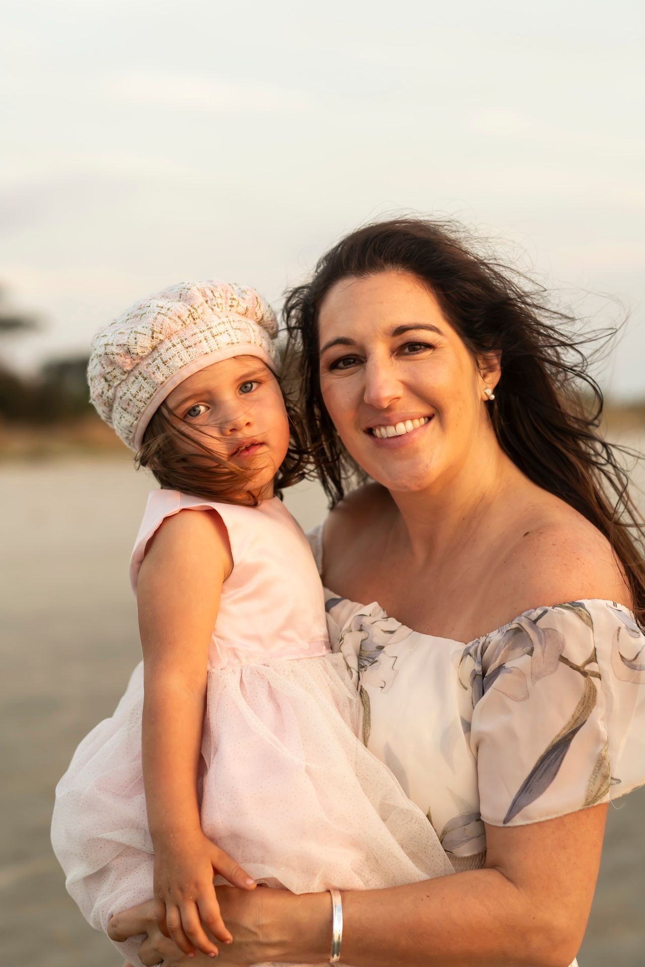 Mother and child sharing a sweet moment together on the beach in warm sunlight.