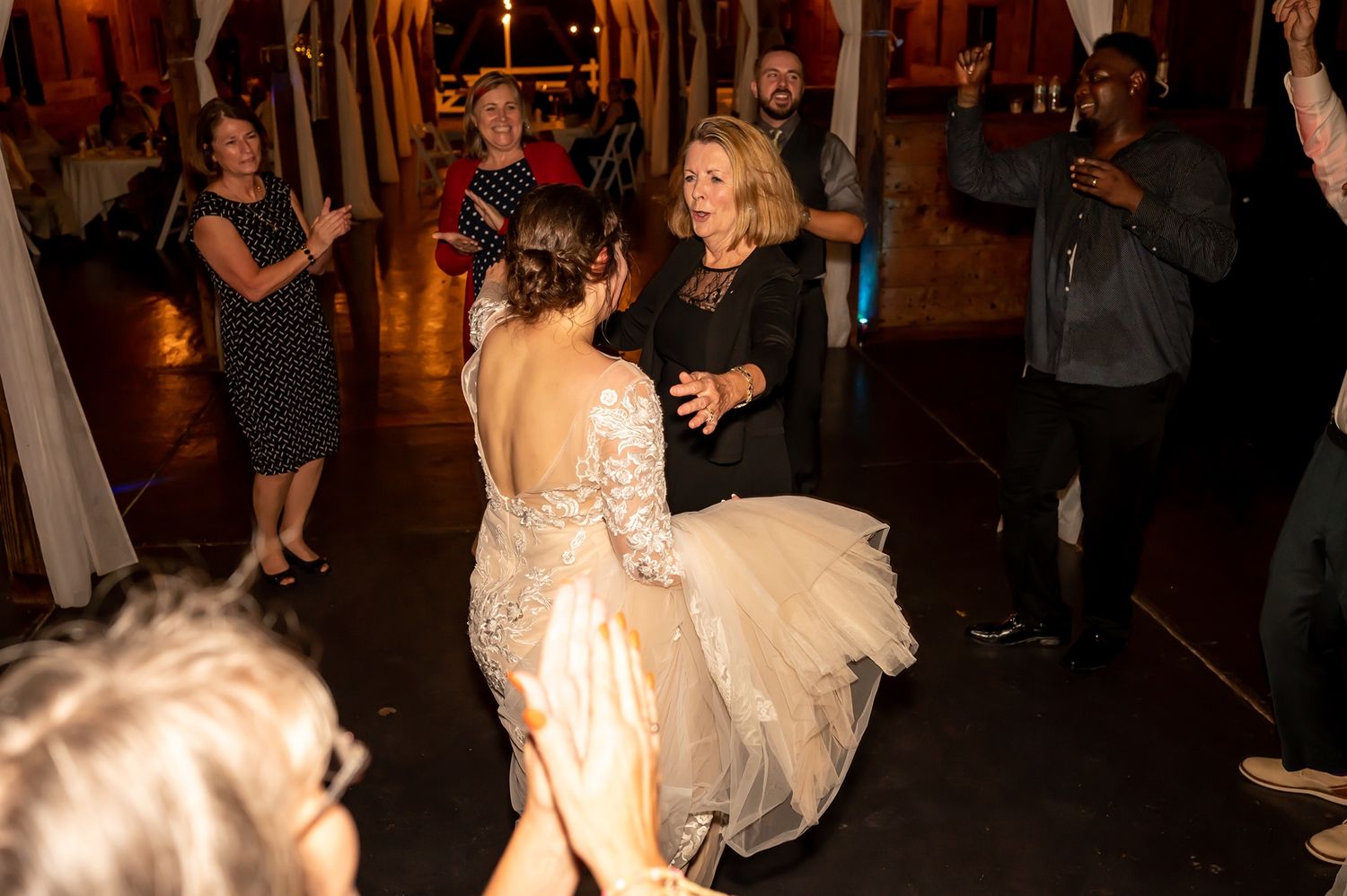 Guests dance and celebrate at an elegant evening wedding reception in a dimly lit venue with warm ambient lighting.