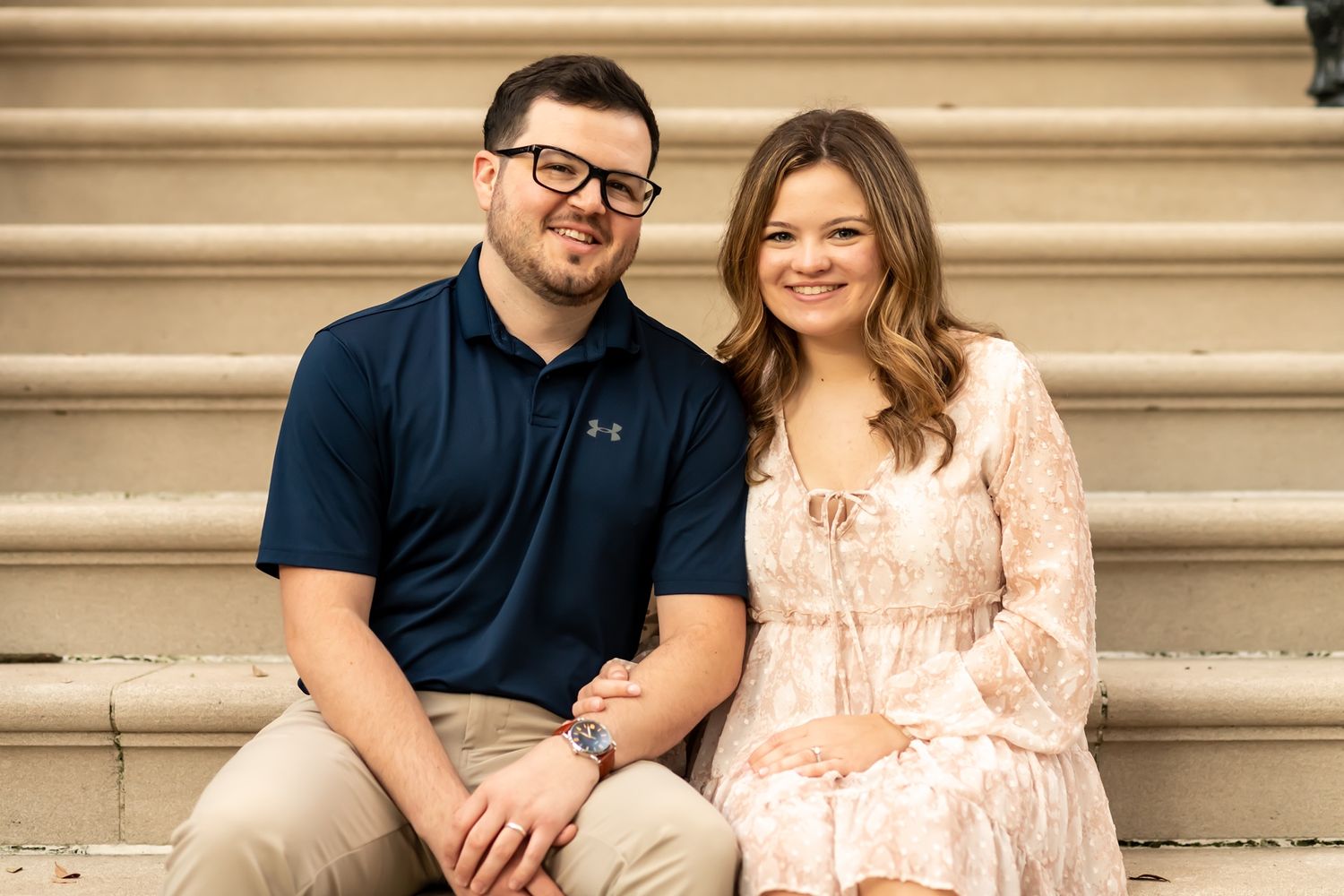 Couple in casual attire sitting together on stone steps during an outdoor photo session.
