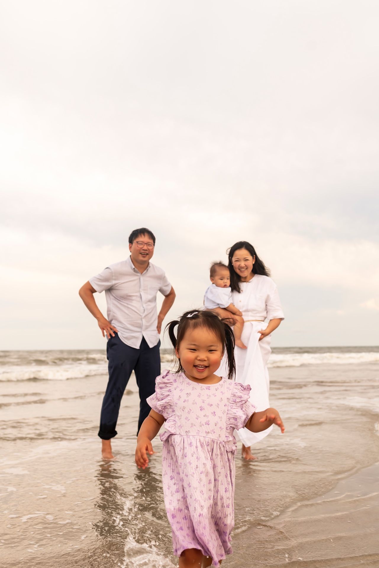 A joyful family playing and splashing together on a beach at sunset as waves roll onto the shore.