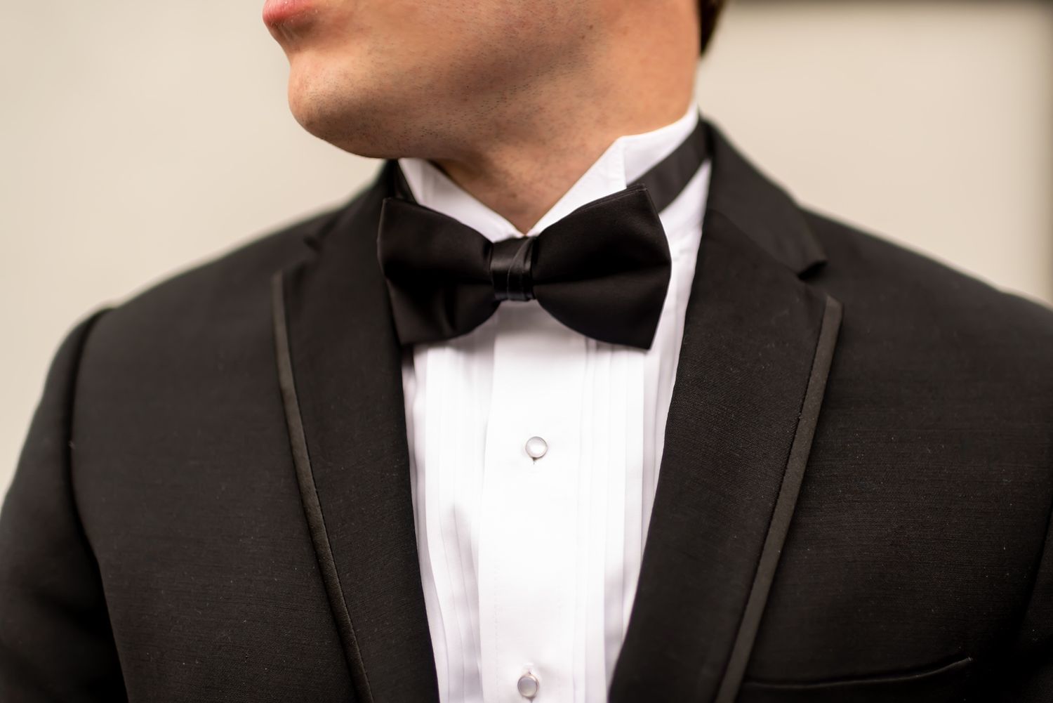 Close-up view of a black bow tie and tuxedo collar on formal attire with crisp white dress shirt.