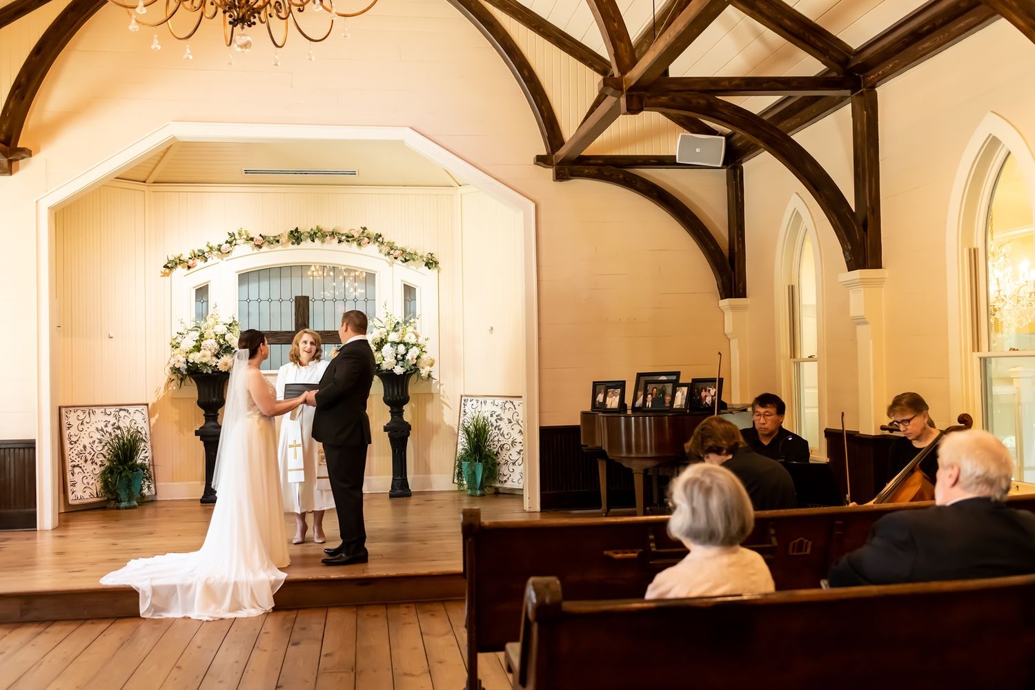 Interior panorama sequence showing a white wedding ceremony venue with exposed wooden beams and decorative floral arches.