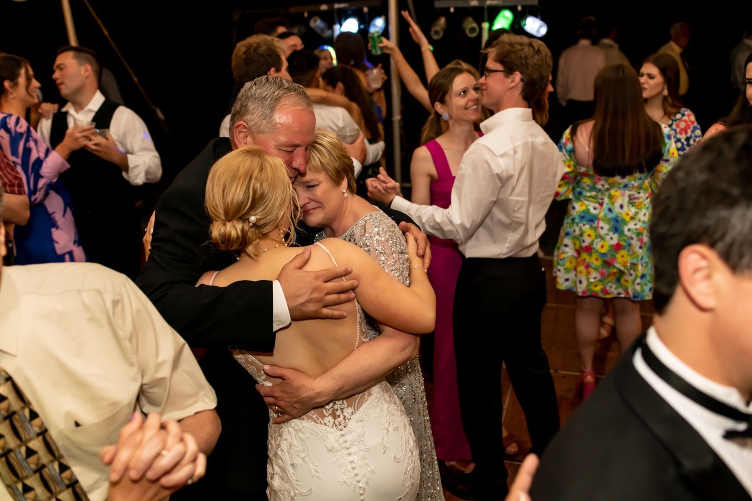 Couples dancing and embracing on a dimly lit dance floor at a wedding reception.