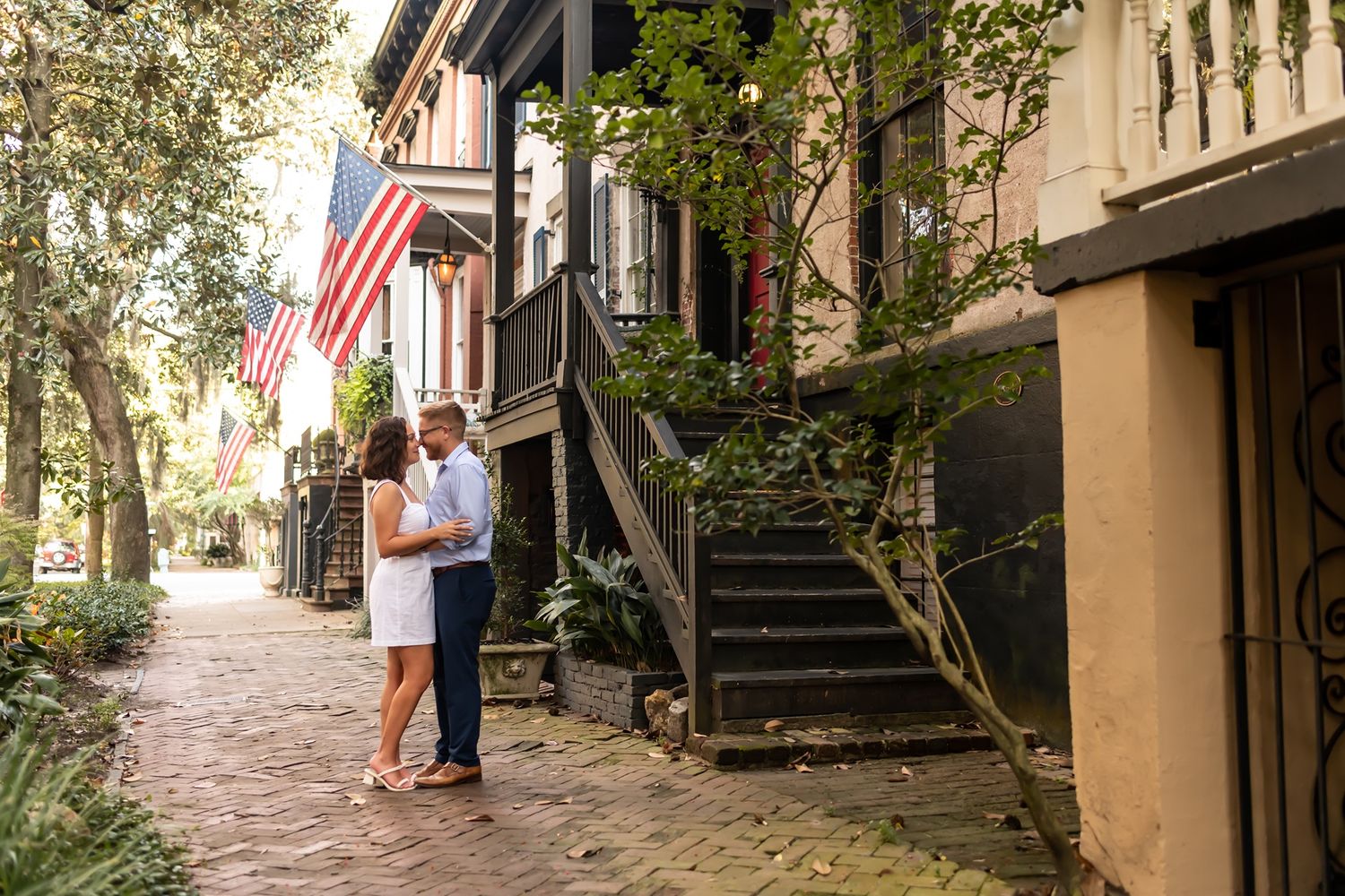 Historic brick-paved walkway through residential alleyway in Charleston with wrought iron balconies and American flag.