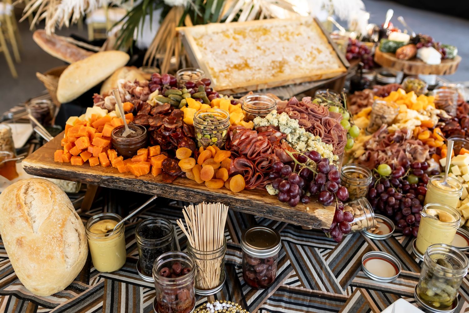 Gourmet charcuterie board with cured meats, cheeses, dried fruits and nuts displayed on decorative patterned surface.