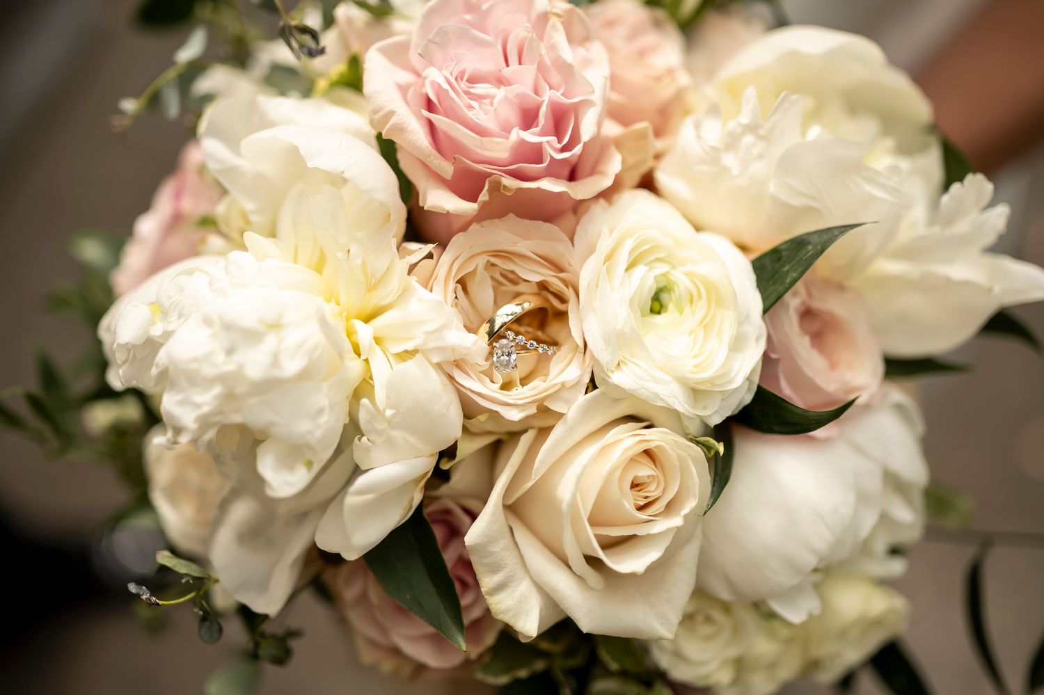 Elegant bridal bouquet featuring blush pink and ivory roses with white peonies in soft natural lighting.