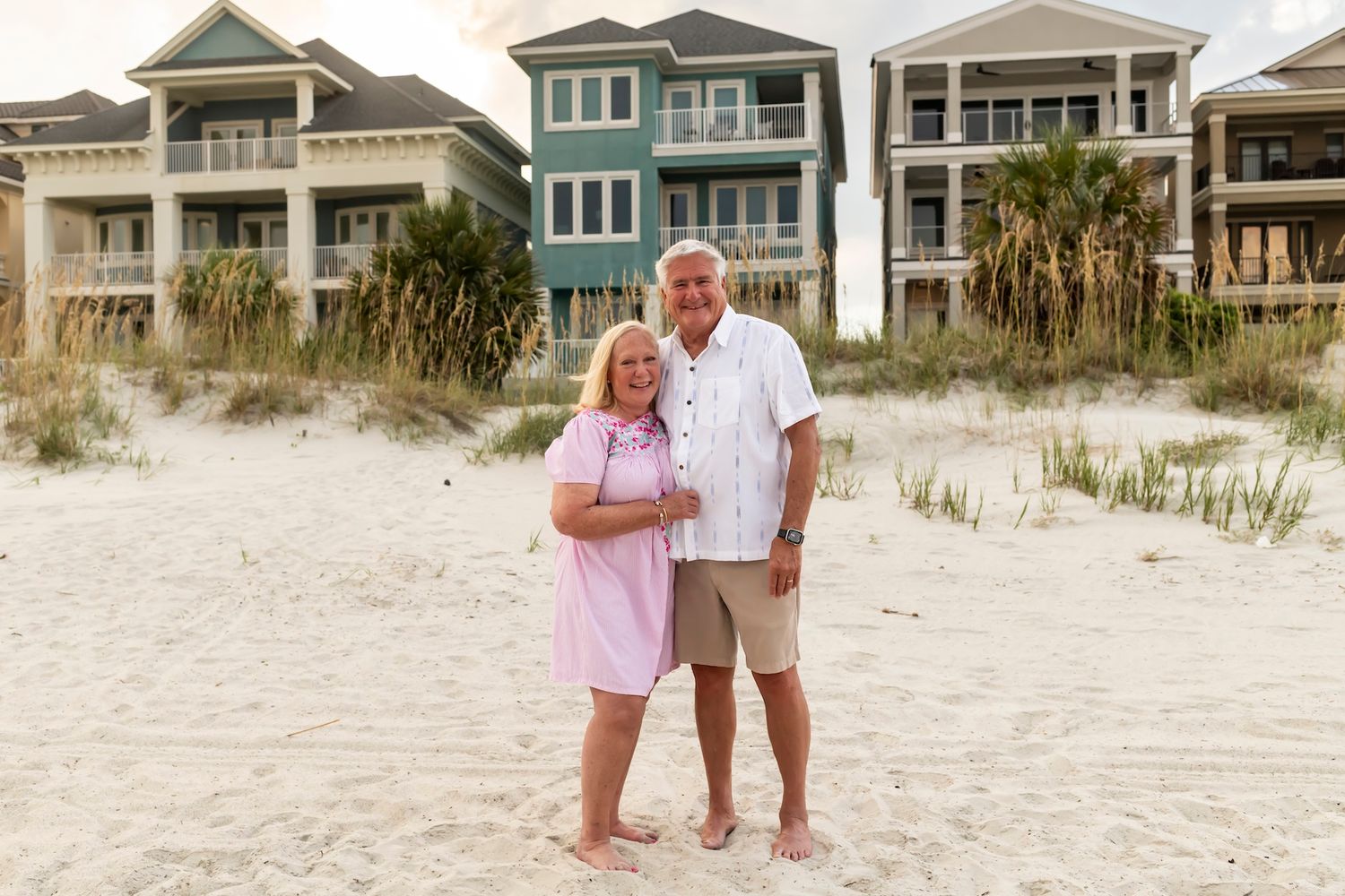 A tender moment between two people walking together on a sandy beach coastline at sunset.