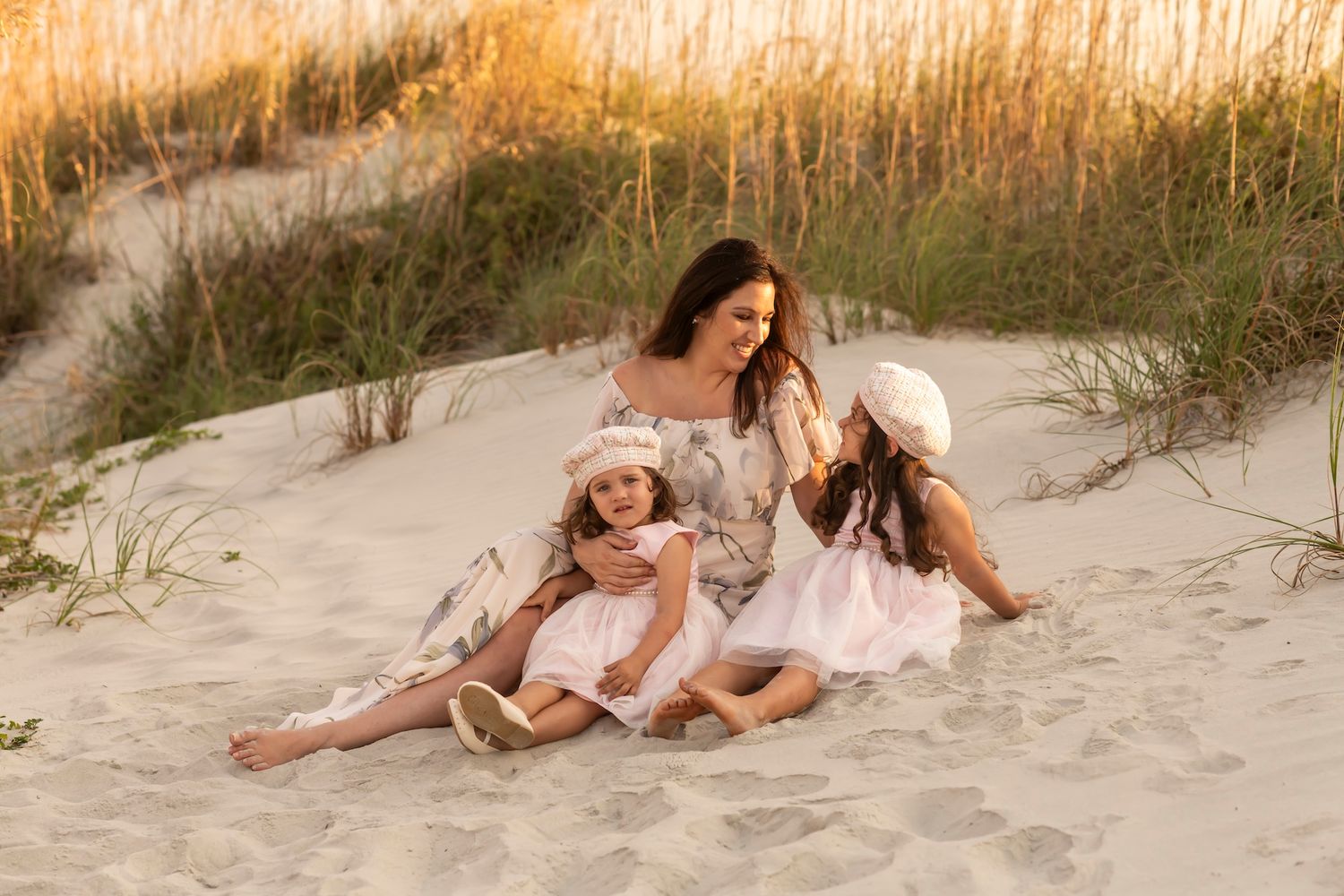Group enjoying tender moments together while lounging on a sandy beach during golden hour.