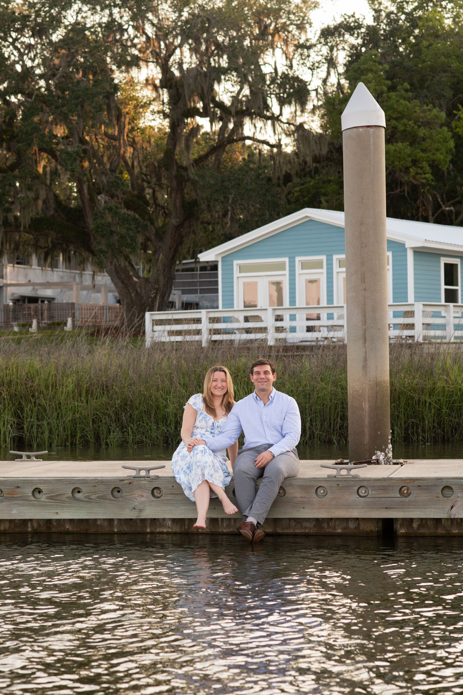 Couple sits together on wooden dock by water during sunset at Isle of Hope Marina.