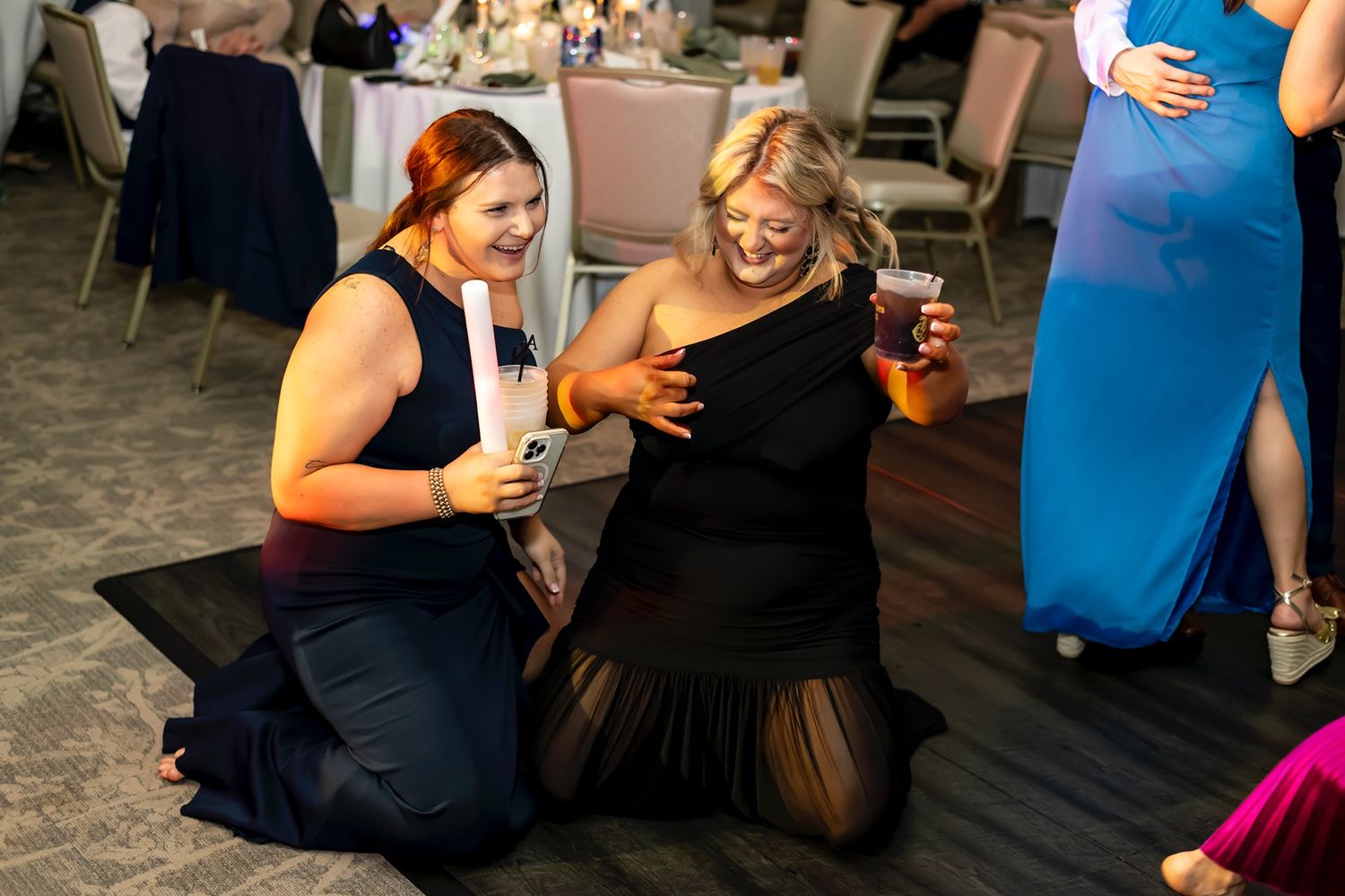 Group of guests gathered in casual conversation at an indoor social event, with vibrant blue lighting visible.