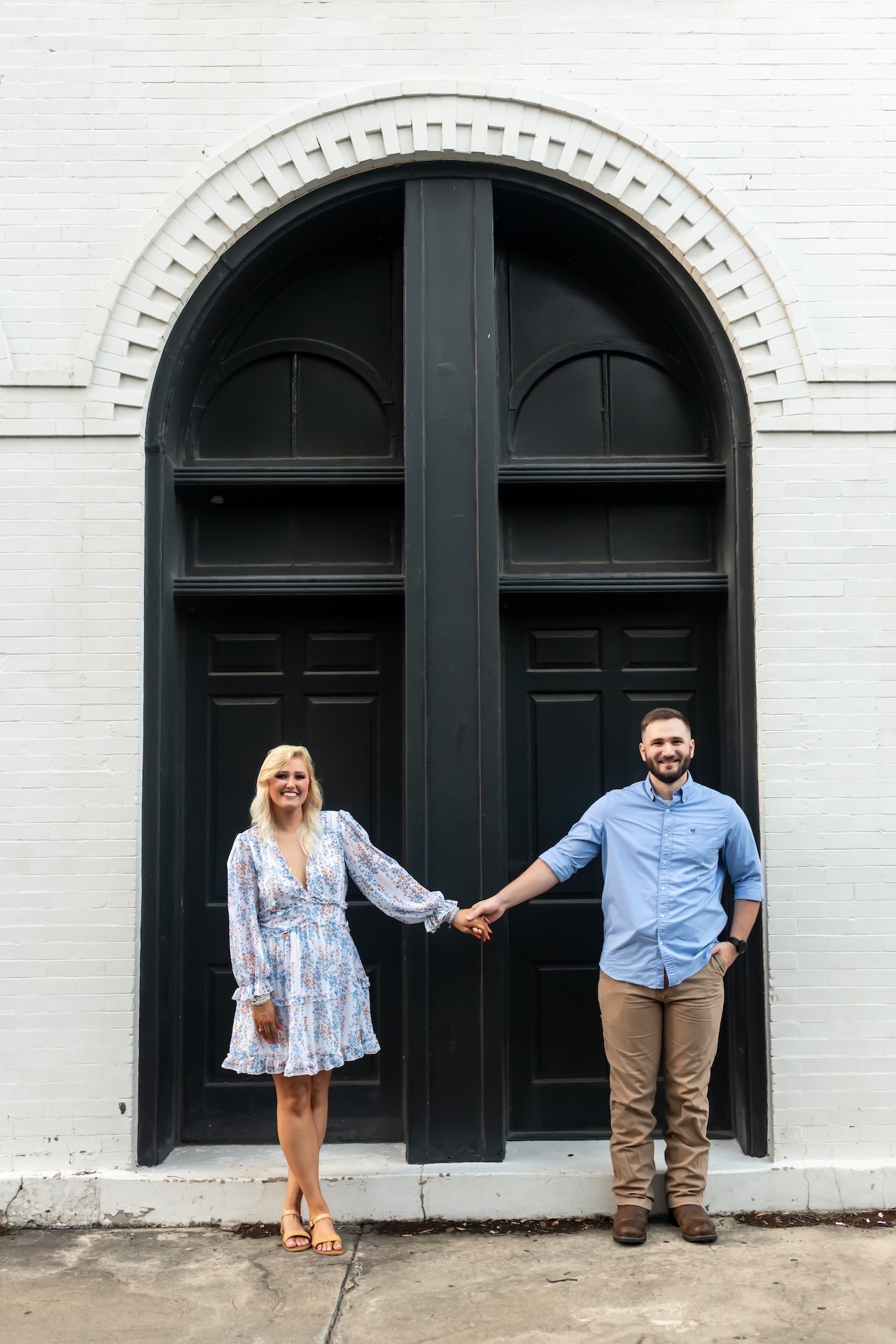 A couple stands in front of a series of arched black doors against a white wall in a progressive engagement photo sequence.