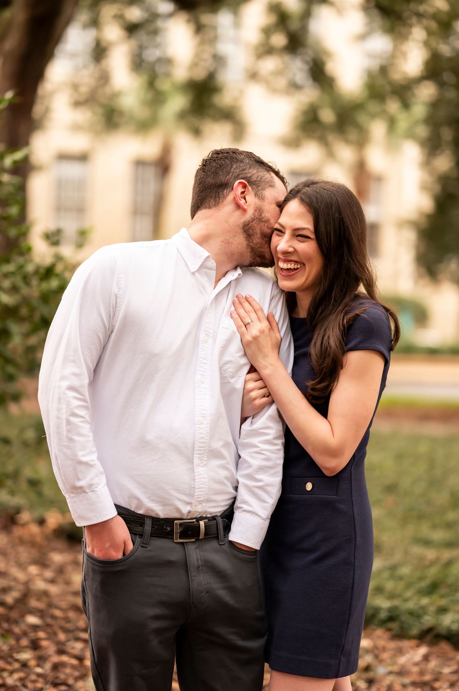 A romantic moment between a couple in formal attire sharing gentle affection outdoors during sunset.