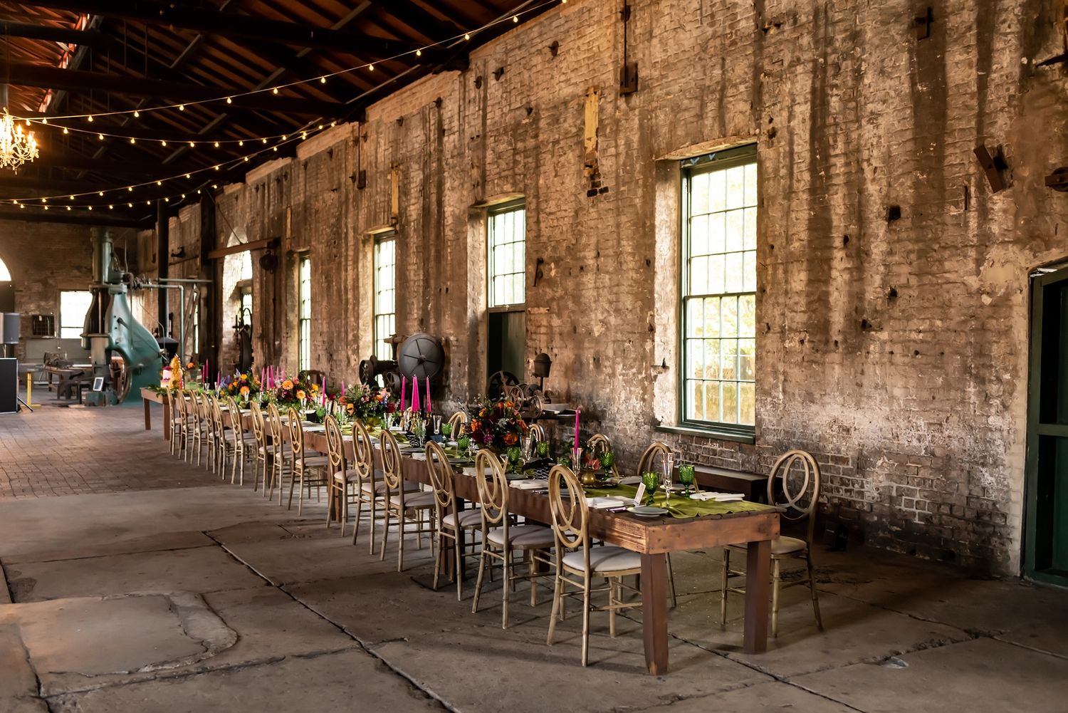 An elegant rustic wedding venue with exposed brick walls, string lights, and vintage-style table settings for a large reception.