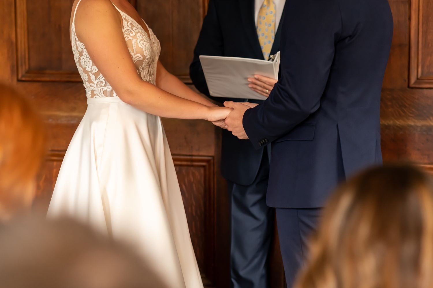 An elegant wedding ceremony setup with formal attire in a traditional wood-paneled room.
