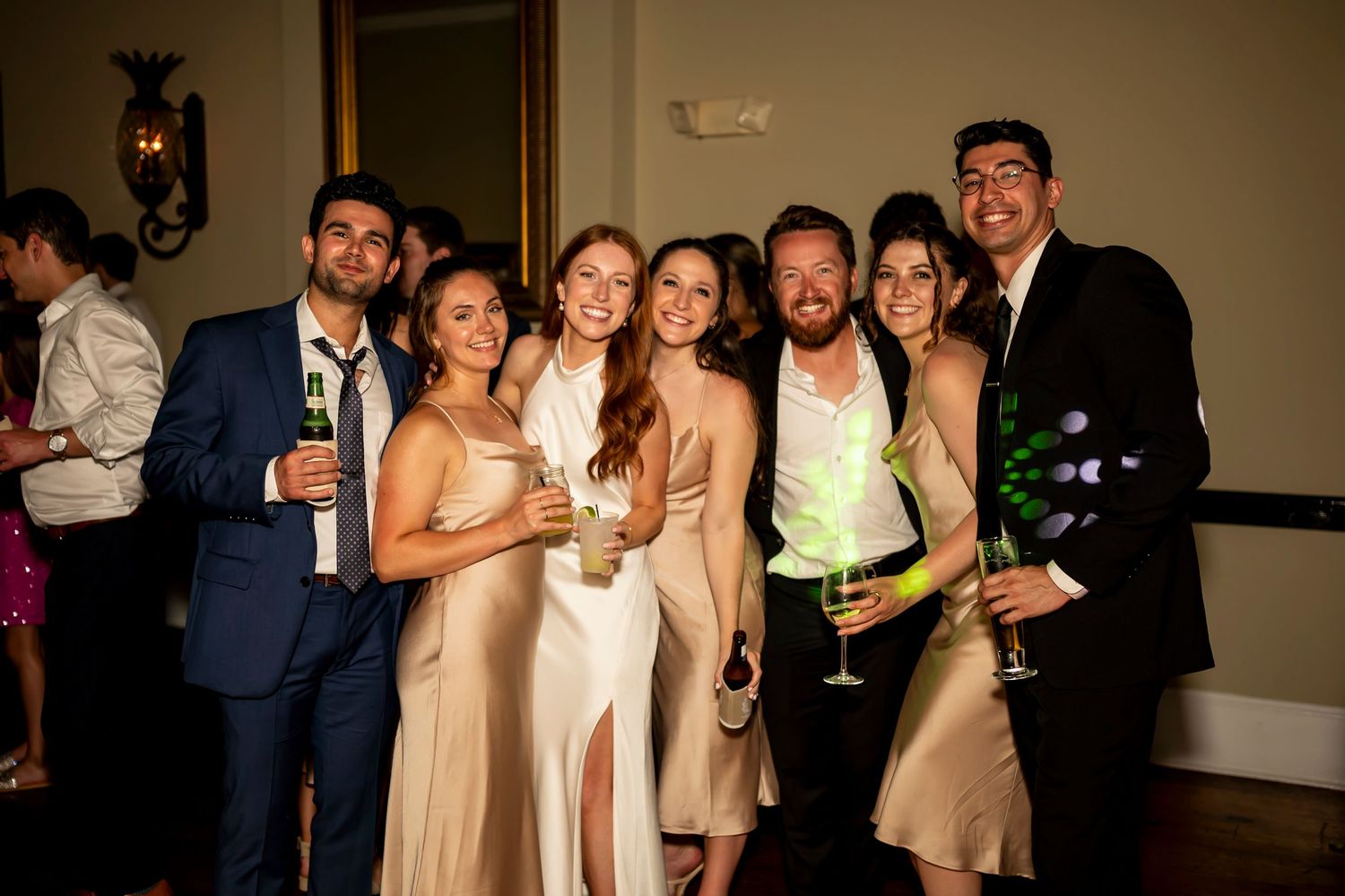 Party guests in formal attire pose with champagne glasses at an evening celebration.