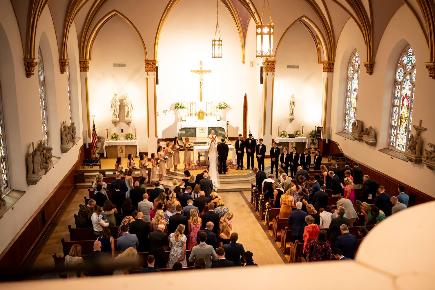 Overhead view of a traditional Catholic church wedding ceremony with guests seated in ornate Gothic-style sanctuary.
