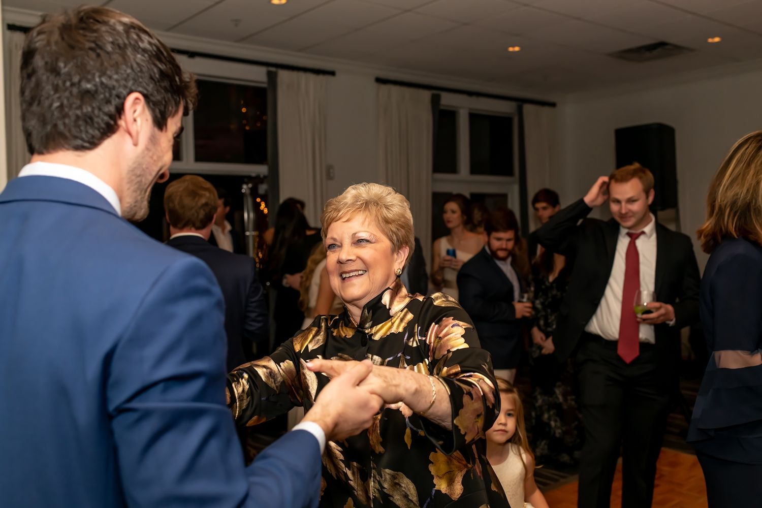People dancing and socializing at an indoor evening event with guests wearing formal attire in a well-lit venue.
