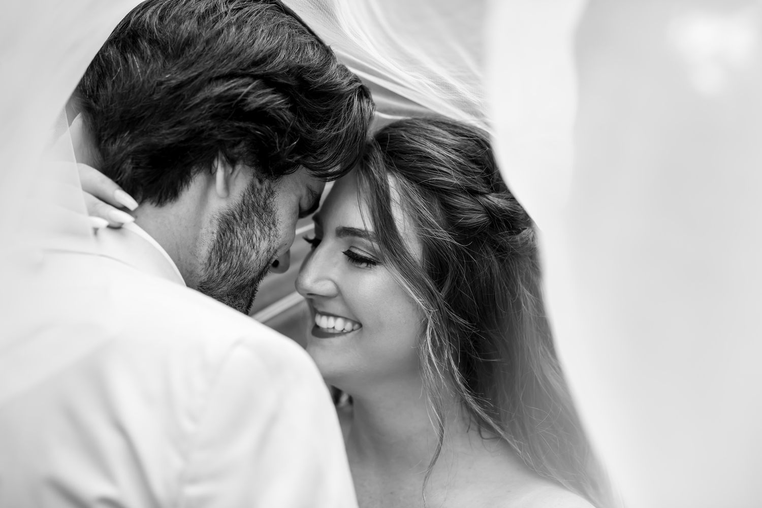 Black and white romantic intimate moment between a couple smiling together, capturing their wedding day joy.