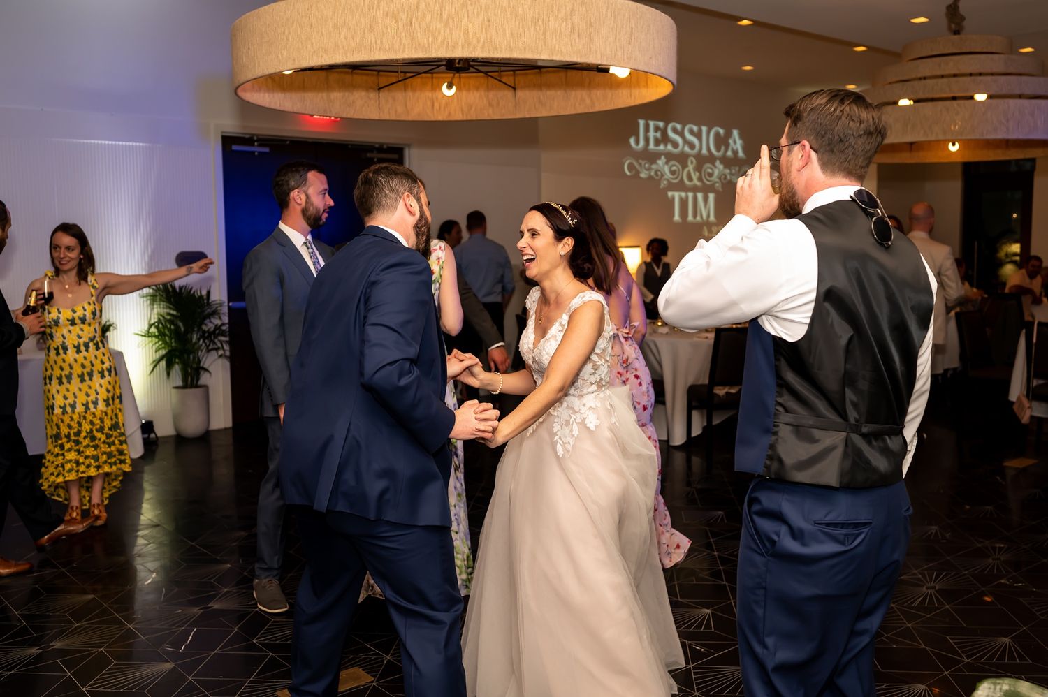 Wedding guests dance and embrace on the reception dance floor during an elegant evening celebration.