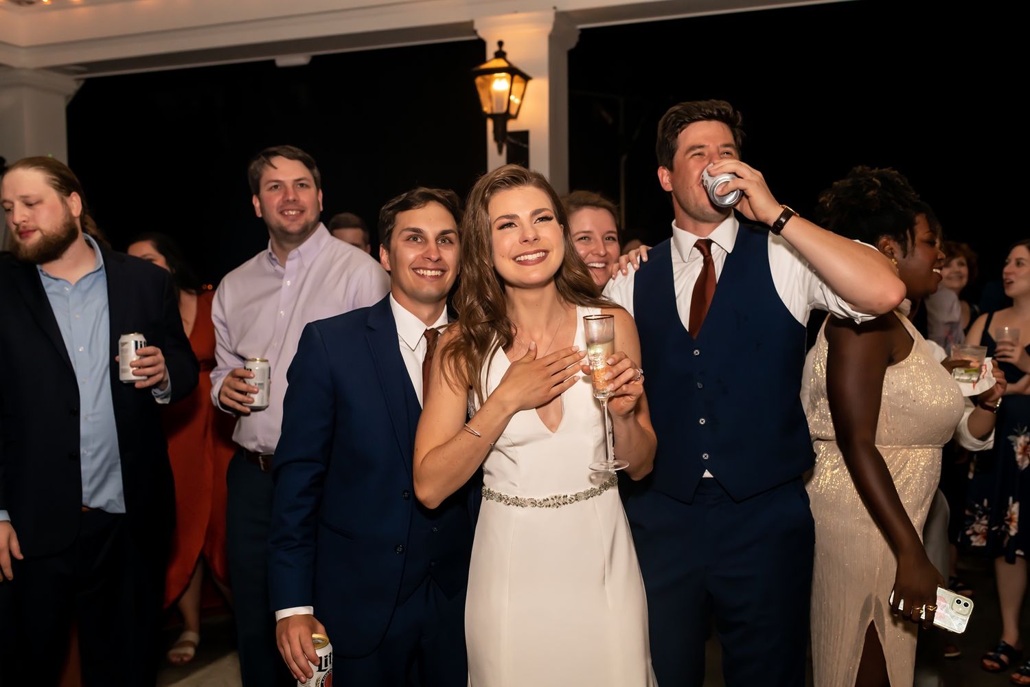Wedding guests dance and celebrate together on a dark dance floor at an evening reception party.