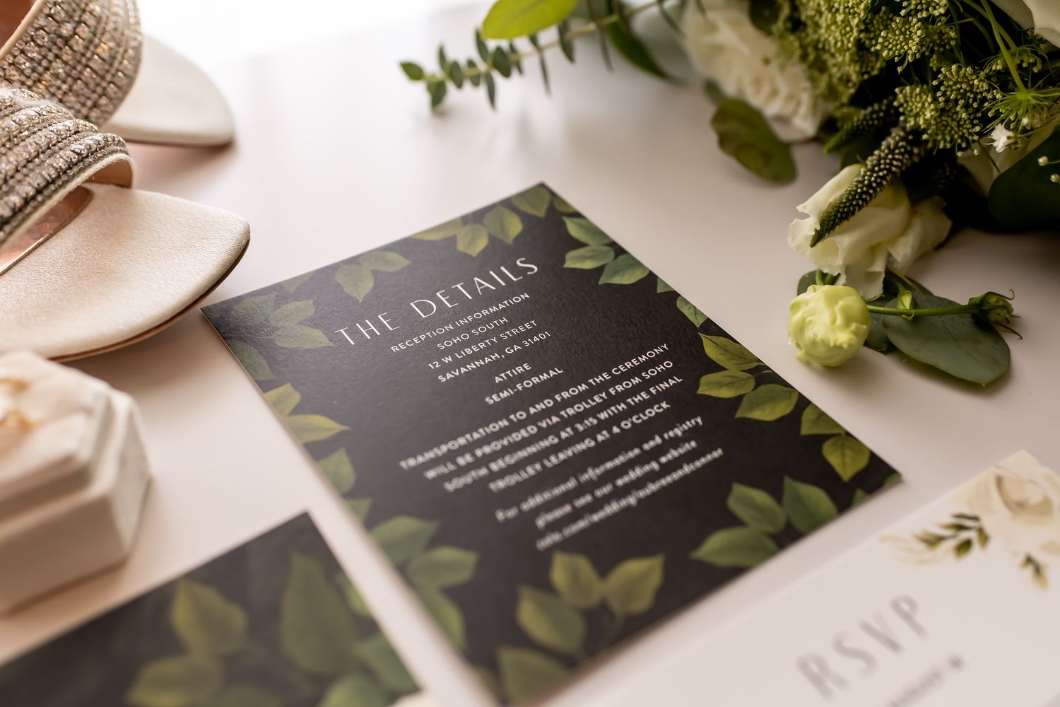 Wedding invitation suite featuring dark gray cards with elegant botanical designs and greenery accents on white surface.