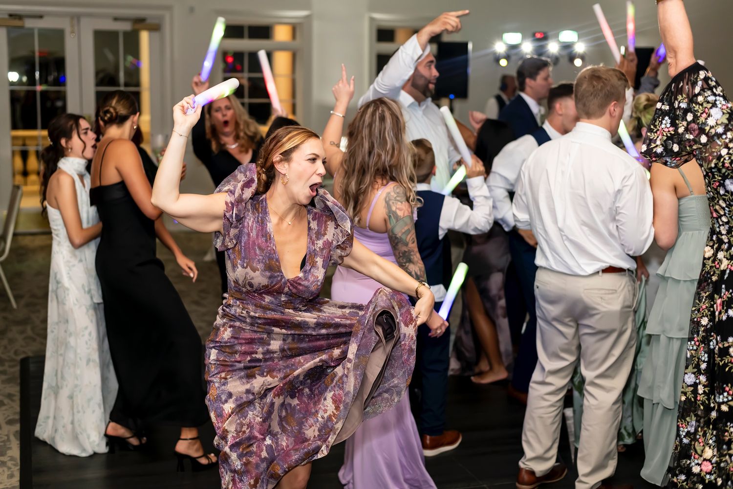 Wedding guests dance and celebrate on a crowded dance floor at an evening reception.