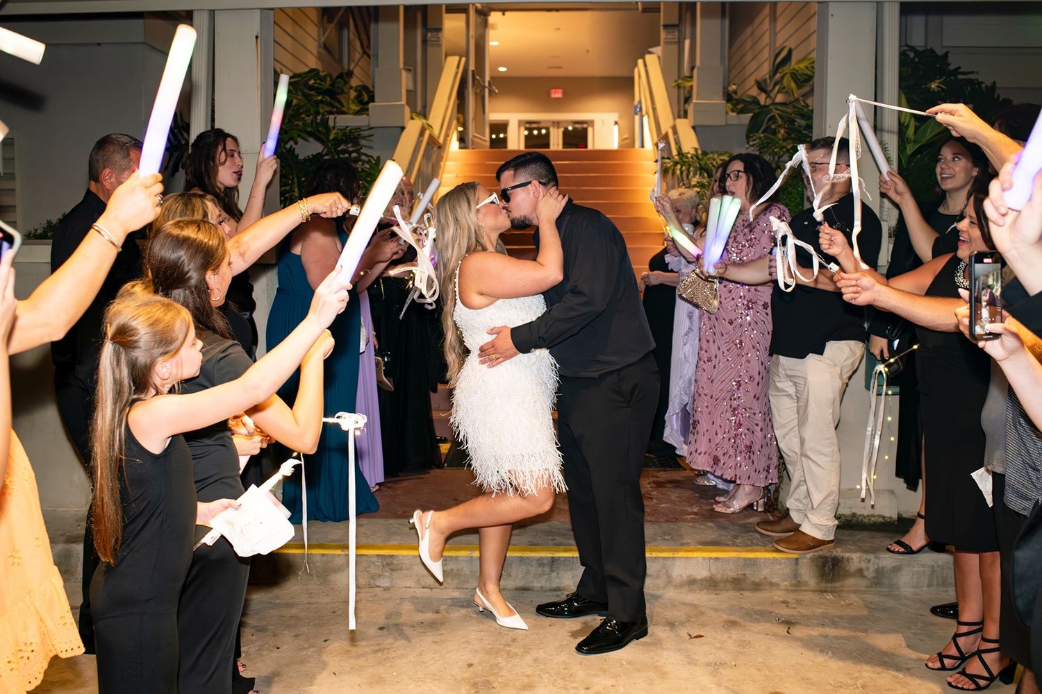 Bride and groom kiss during their ribbon wand exit  at their Shipyard Beach Club wedding.
