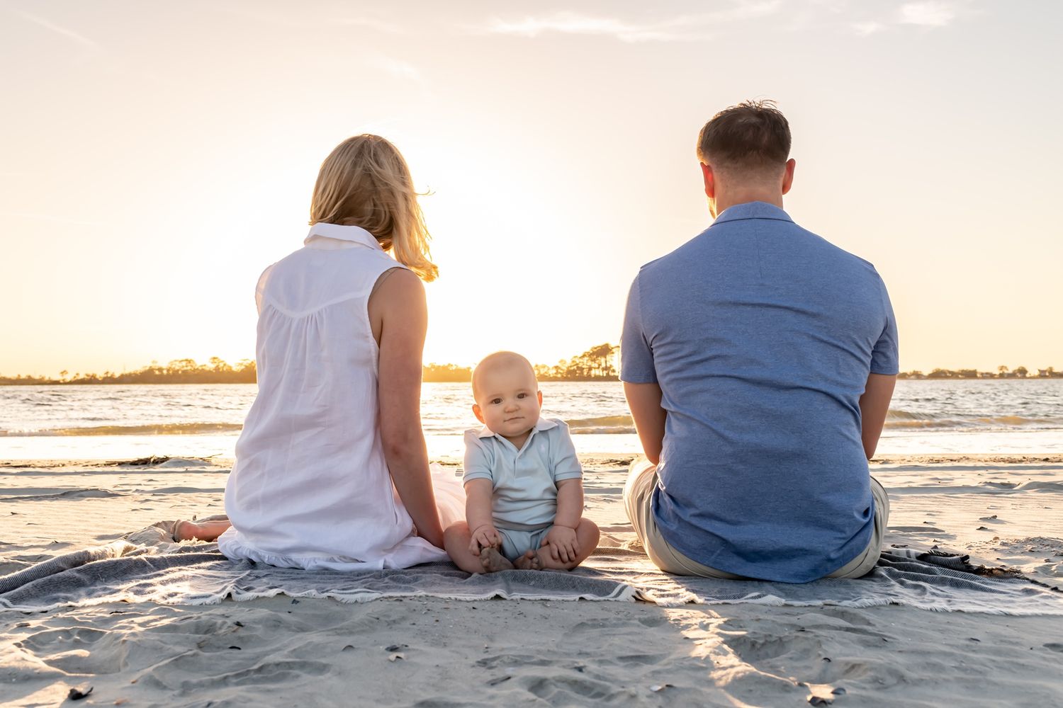 Family spending time together watching sunset at the beach as five connected photos blend into one panoramic scene.