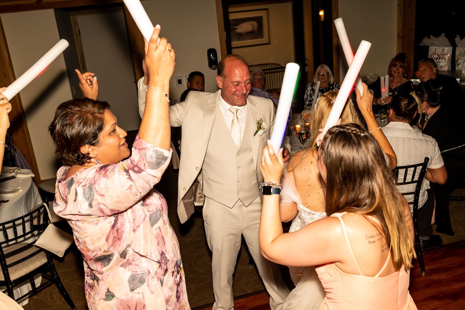 Wedding reception guests dance and celebrate with glowing LED light sabers on the dance floor.