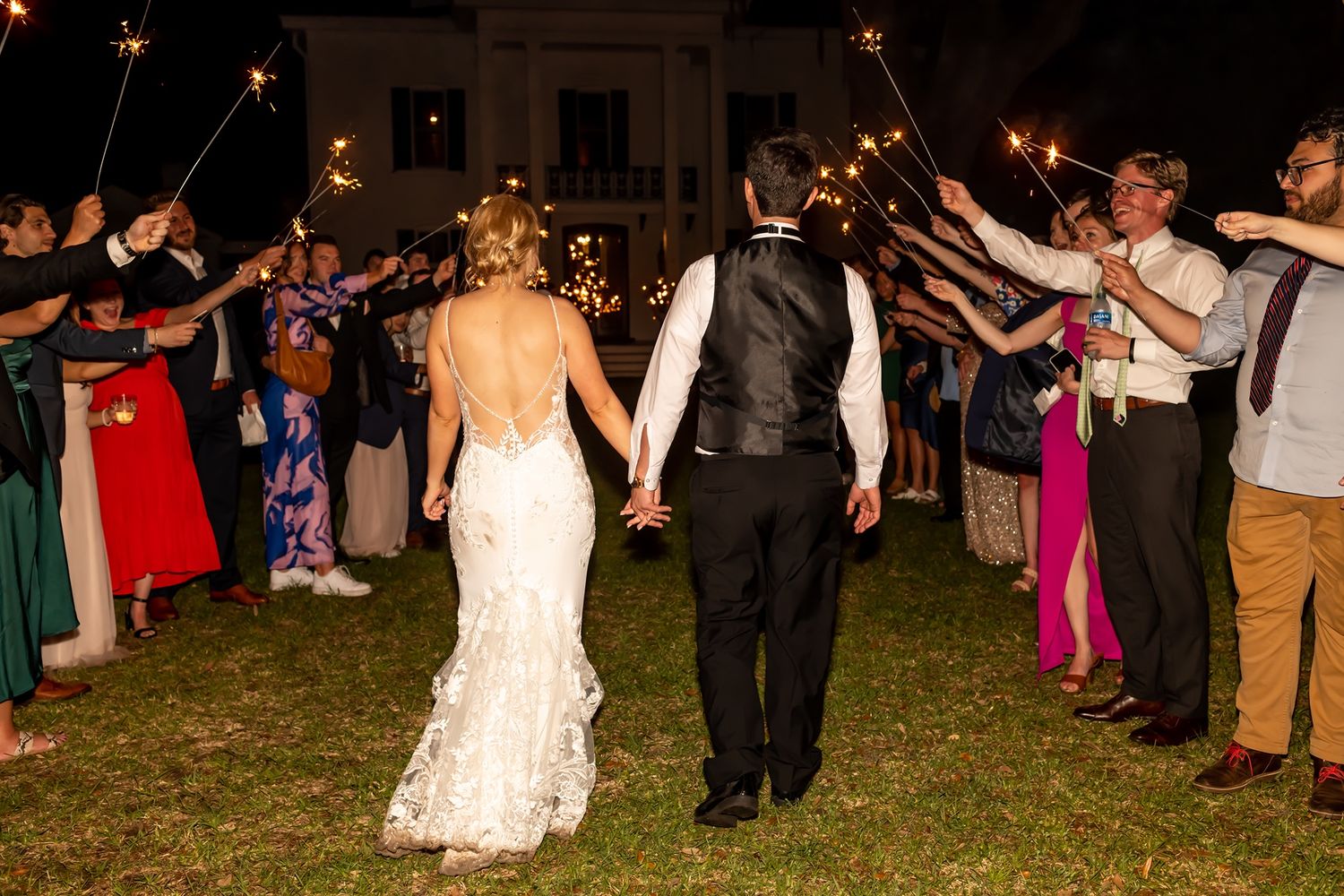 Wedding guests gather under glowing string lights at a festive outdoor nighttime celebration.