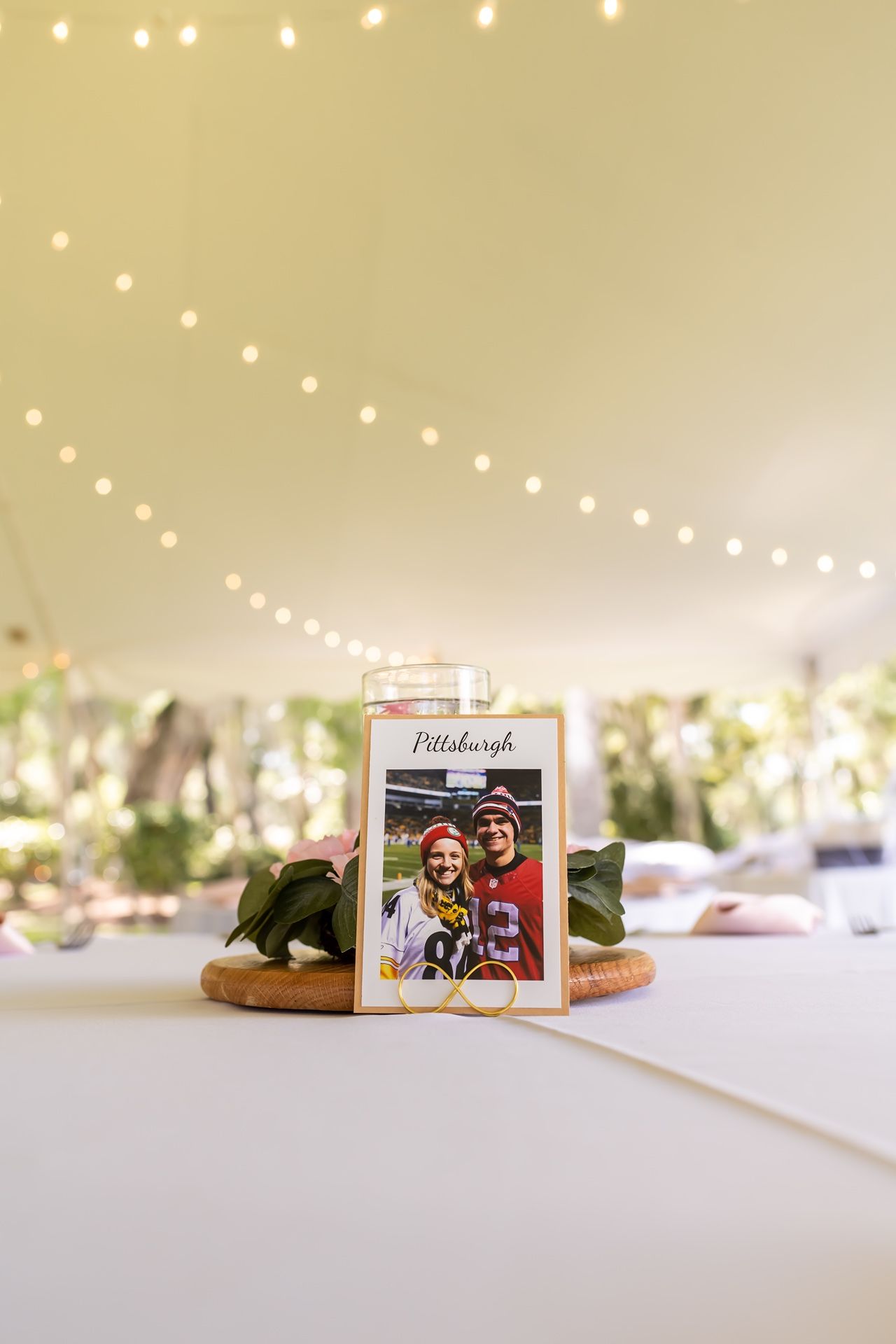 String of decorative lights illuminate photo cards and ornaments displayed on a soft white surface in a minimalist setting.