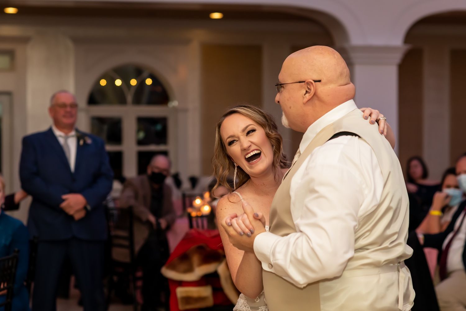 Dancing couples enjoying a wedding reception in a dimly lit ballroom.
