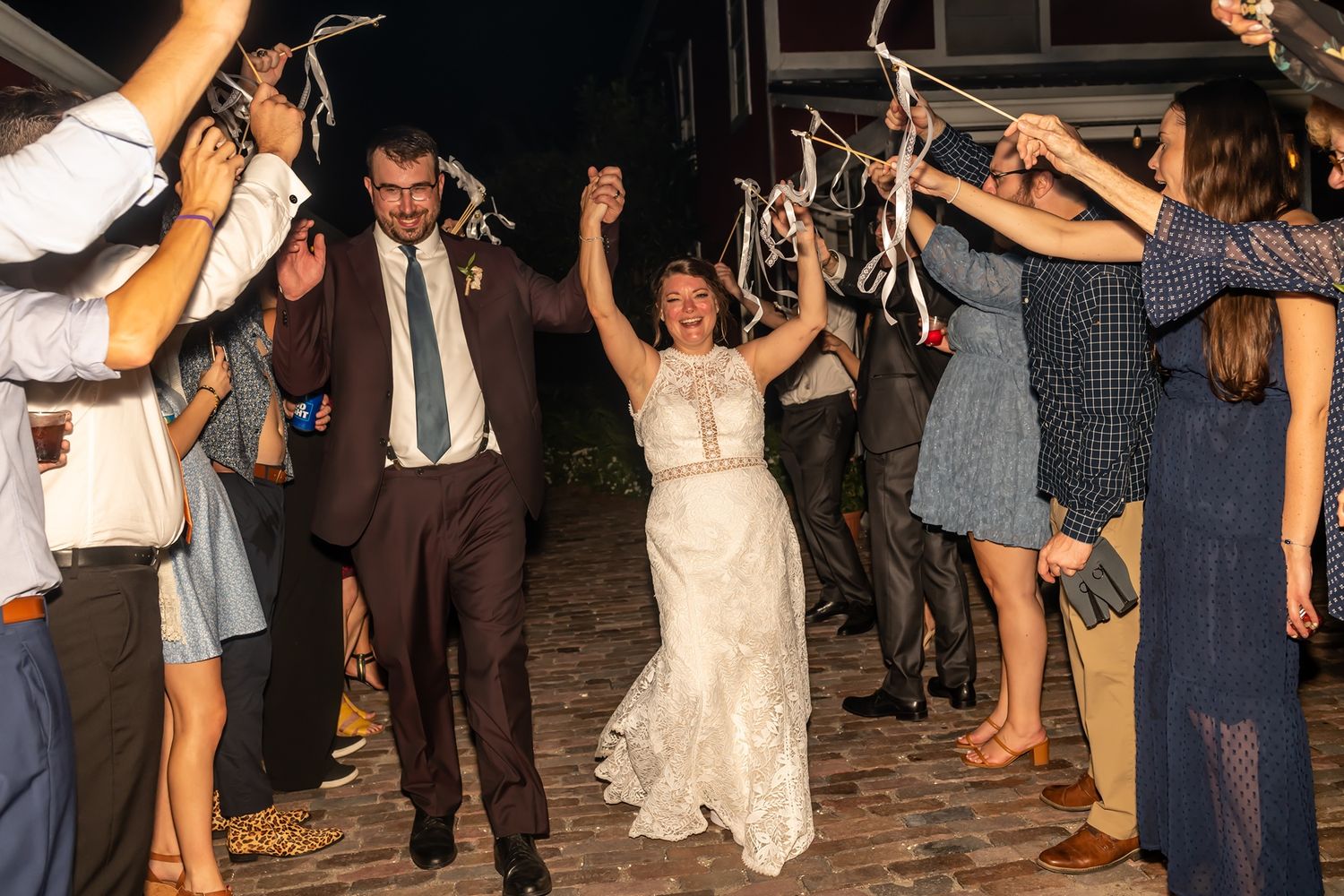 Wedding guests dance in a conga line at an indoor reception celebration during a joyful evening party.