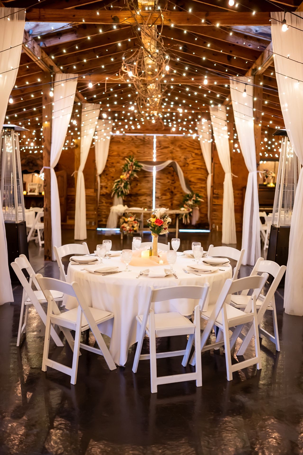 Rustic barn reception venue decorated with twinkling string lights and white table settings.