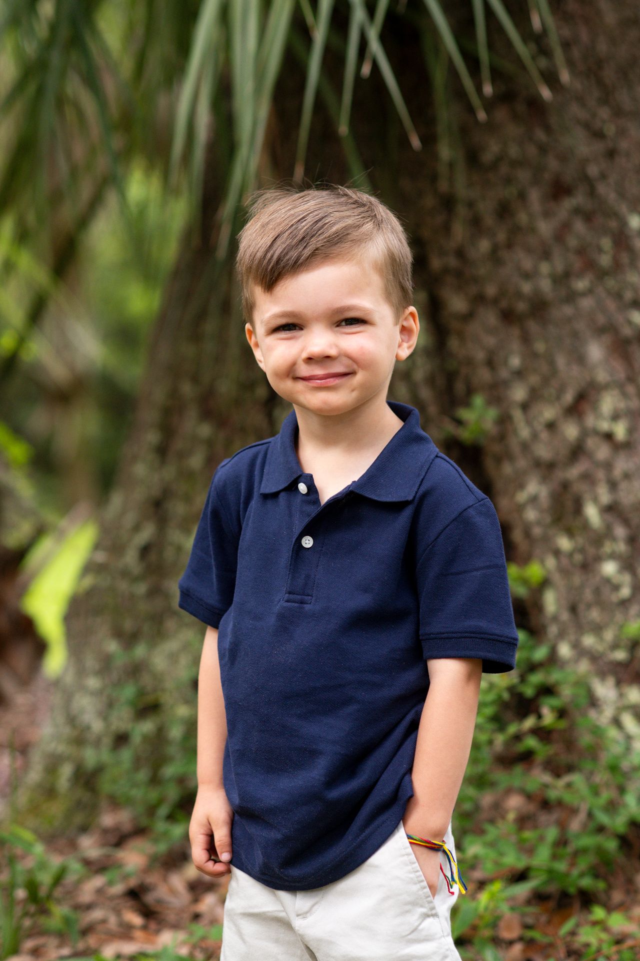 A series of candid outdoor portraits showing a young child in a navy polo shirt and white shorts against a natural background.